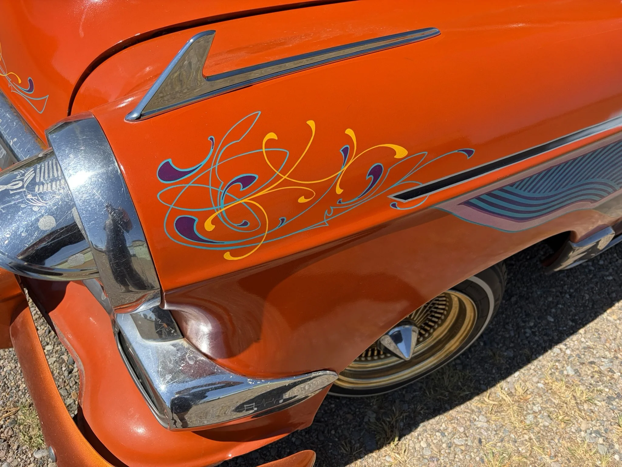 Orange lowrider fender with turquoise, purple, and chrome yellow pinstriping by Matt Beckner.