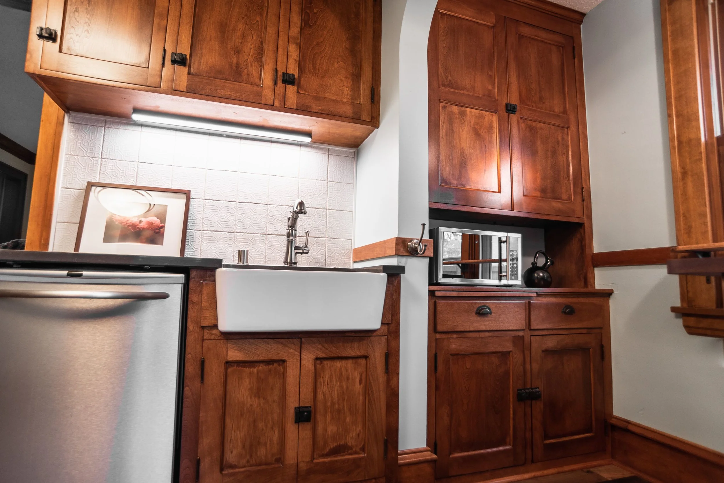 Kitchen remodel with updated cabinets, flooring, appliances, and farm house sink.