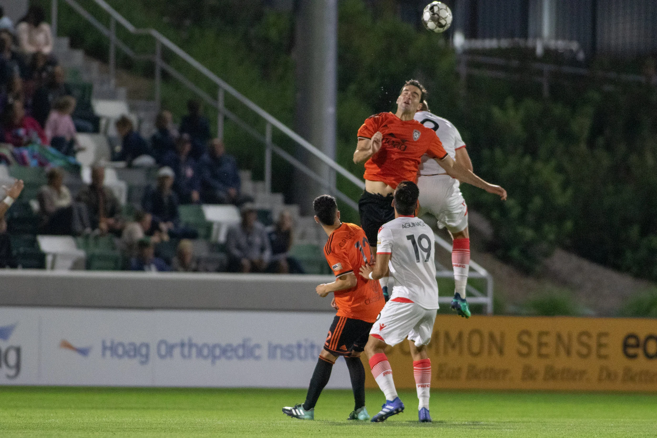 Walker Hume (right) using all of his height to clear a ball against Phoenix Rising FC in May. The center back will be tasked with knocking crosses down or putting them on frame on Sunday. Photo courtesy of Liza Rosales/Orange County SC .
