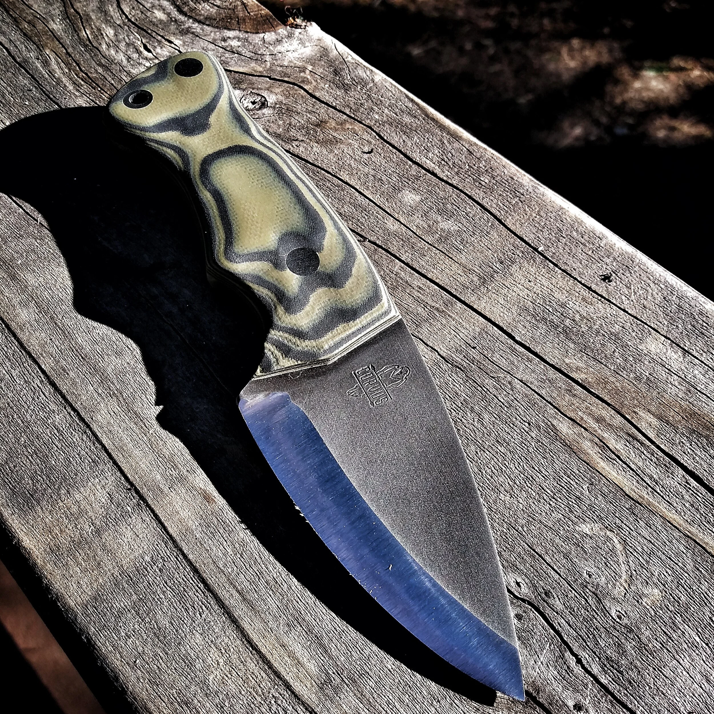 A knife resting on a flat wooden surface.