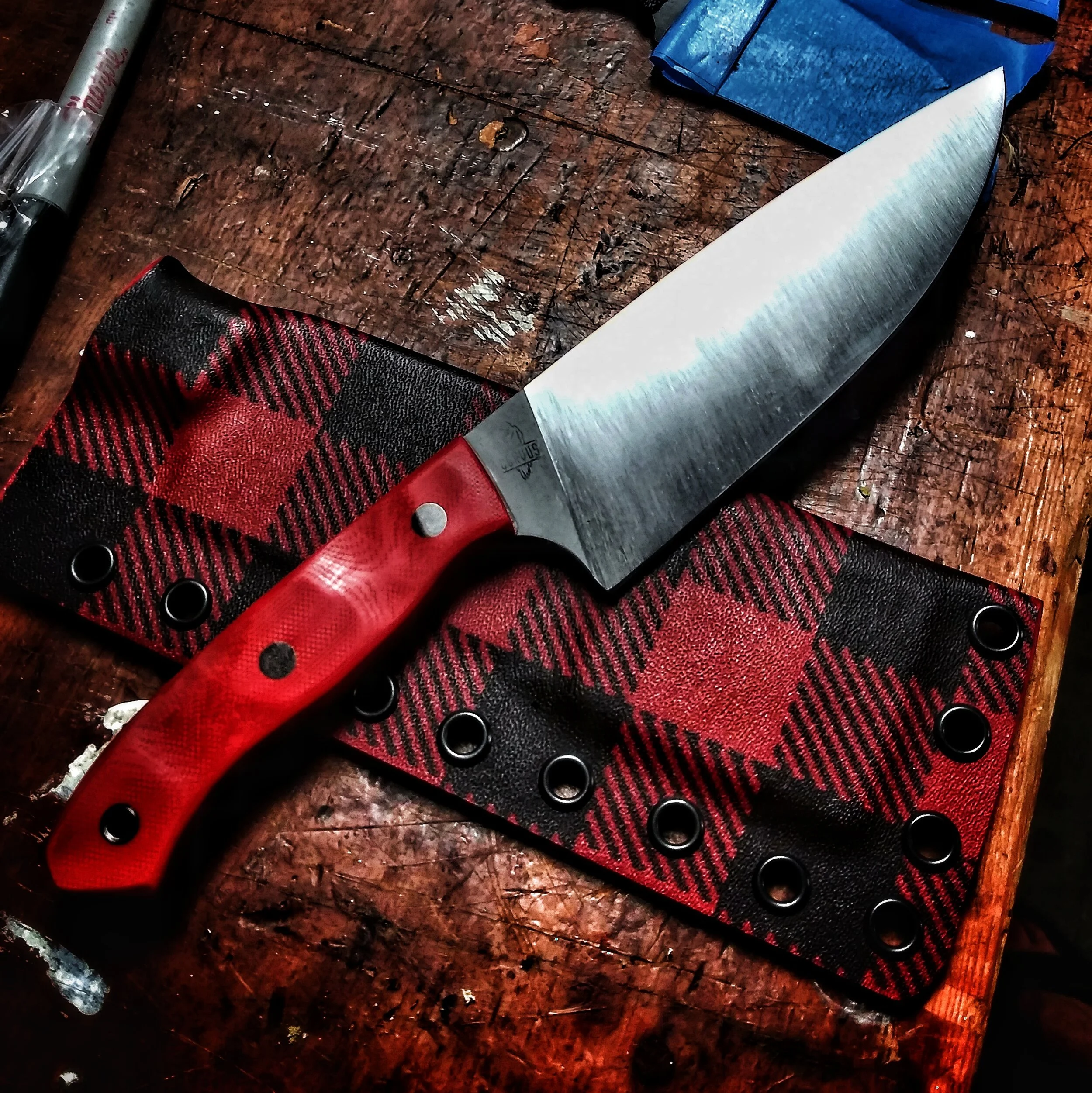 A knife laying on some plaid cloth.