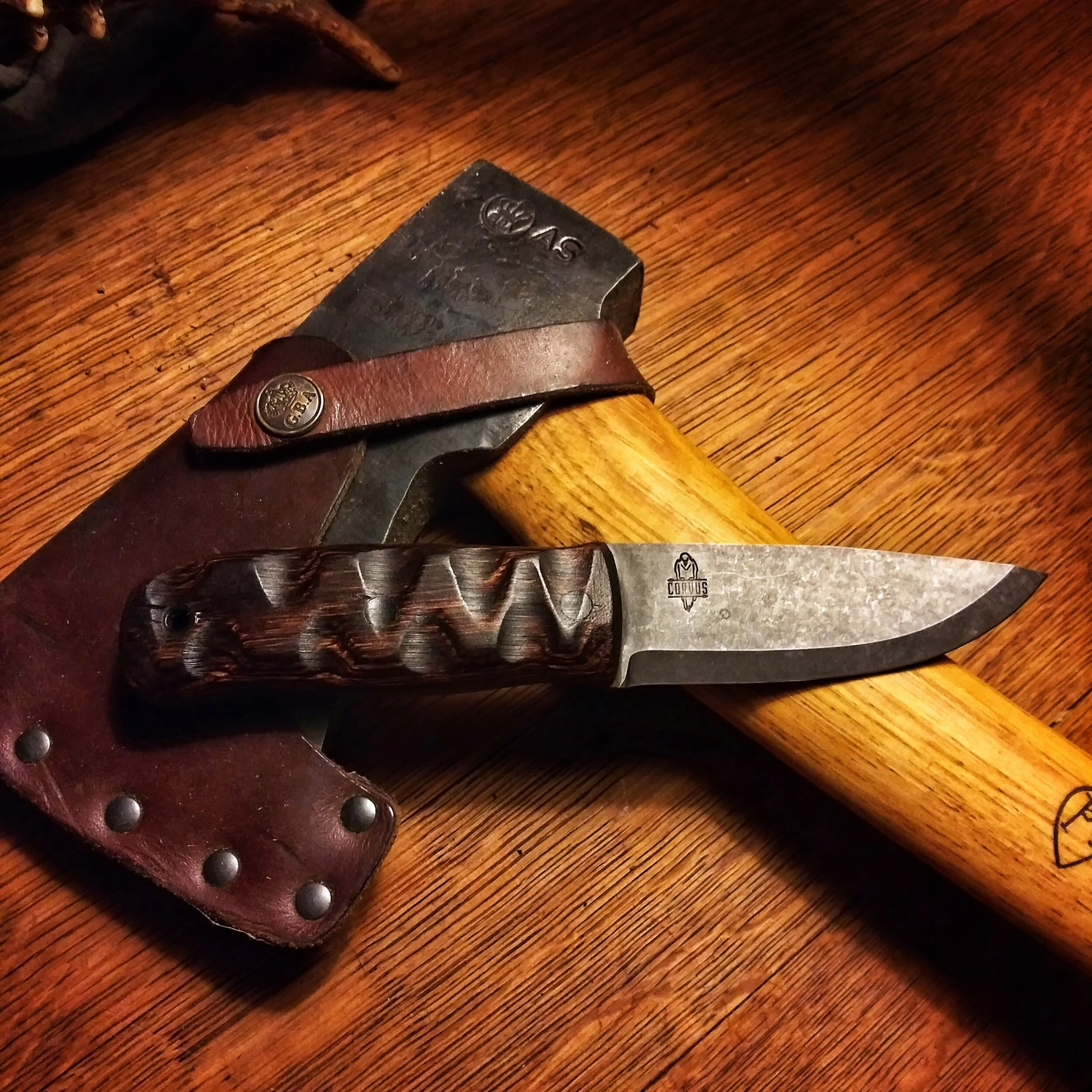 A knife resting on top of a hatchet.