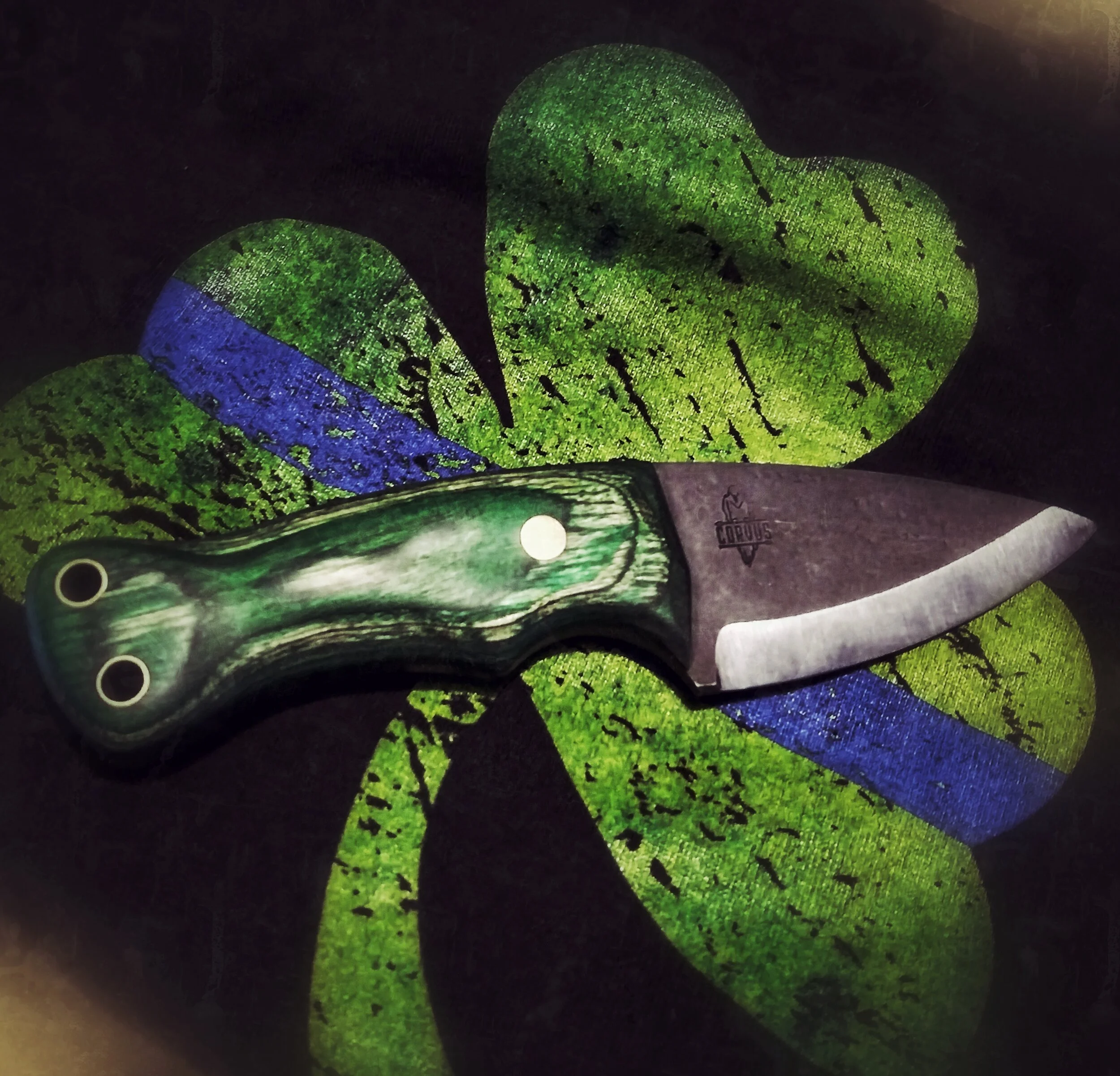 A green-handled knife laying on top of a painted four-leaf clover.