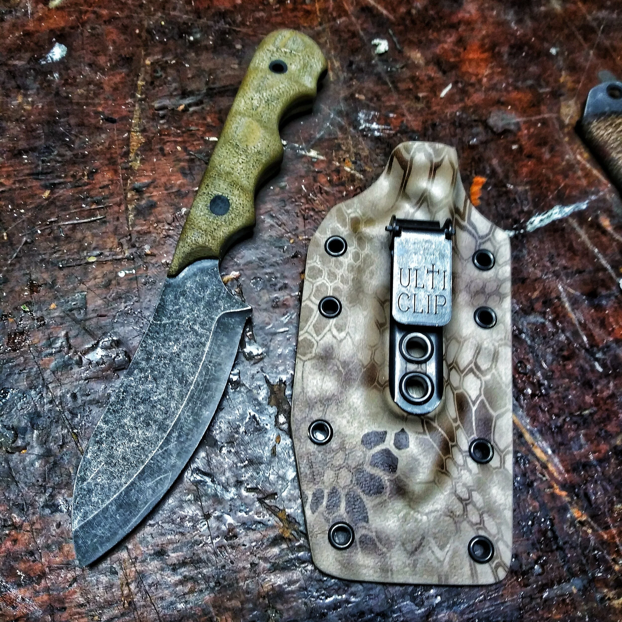 A hammer-finished knife laying beside its sheath.