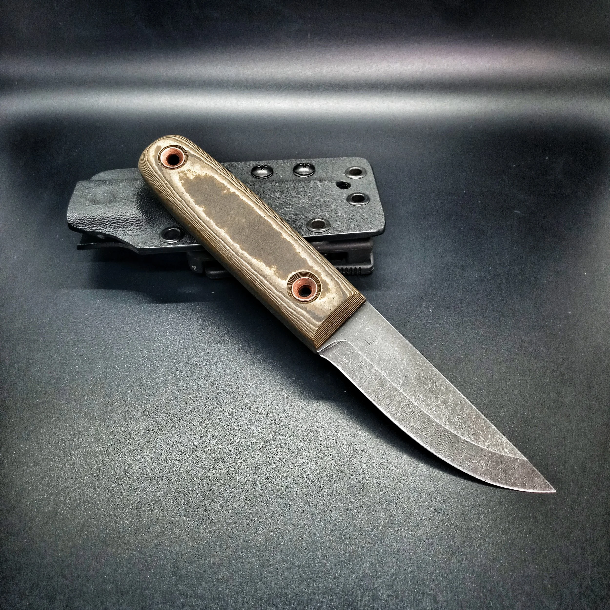 A brass-handled knife resting on its sheath.