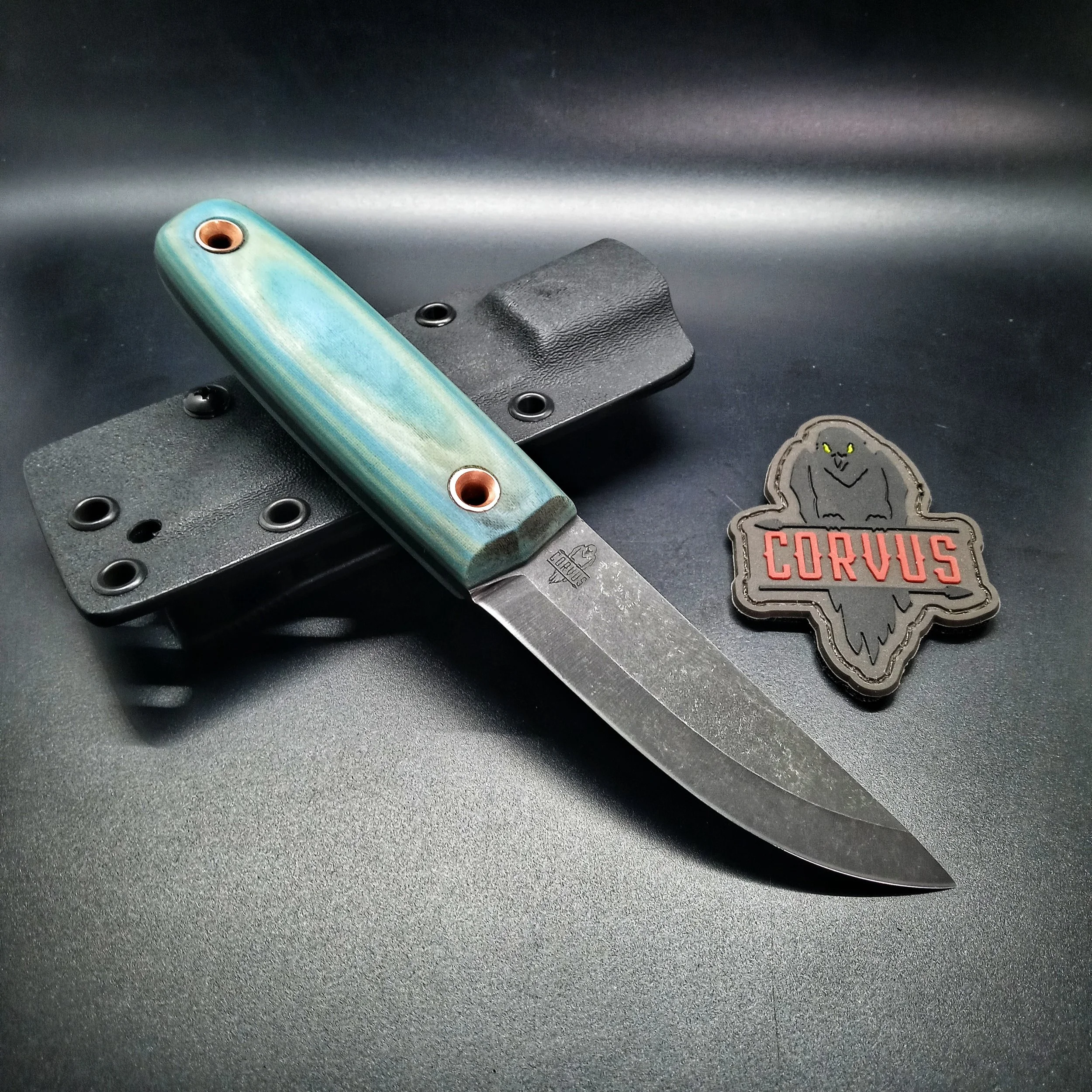 A knife laying on its sheath next to a patch.