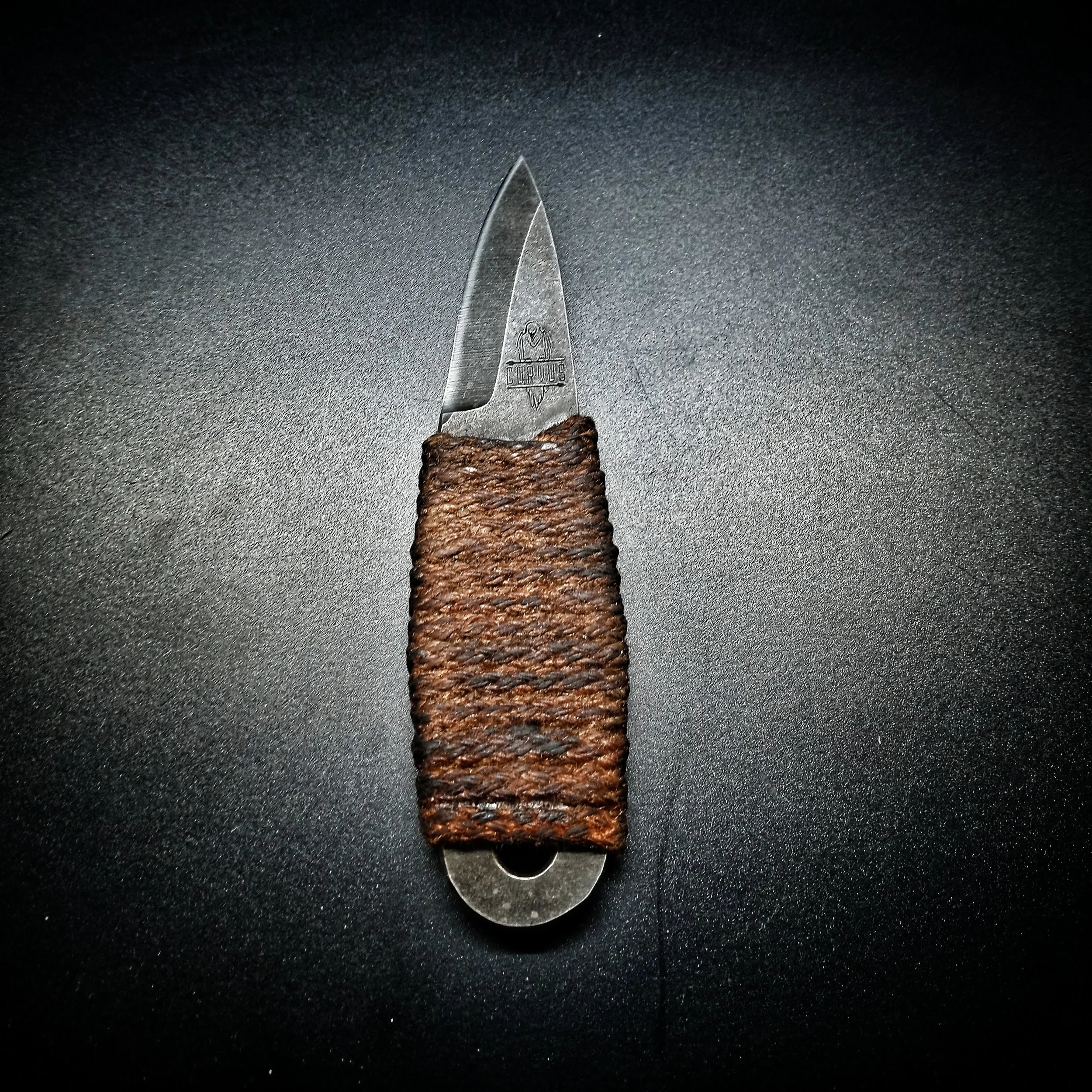 A knife laying on a flat, black surface.