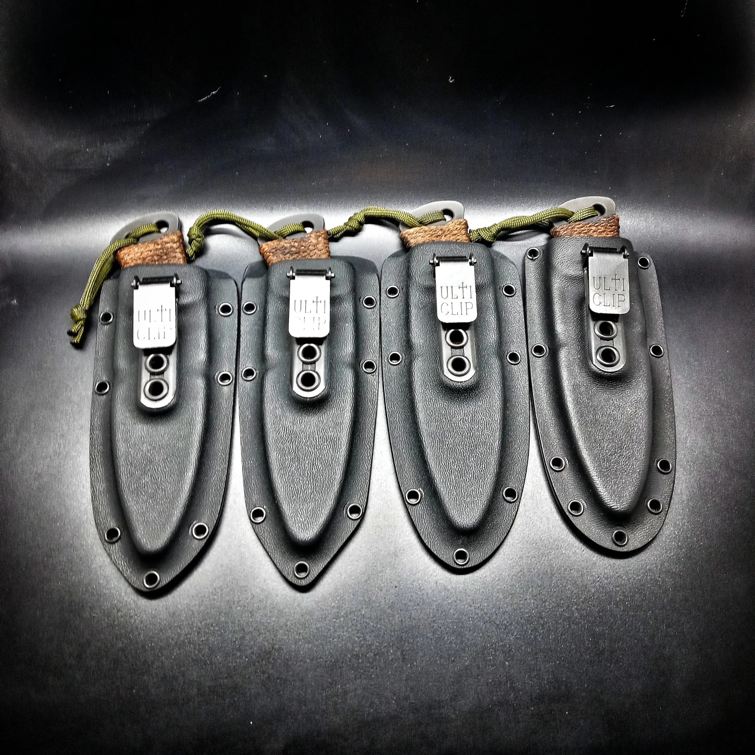 Four knives laid side by side in their sheaths.