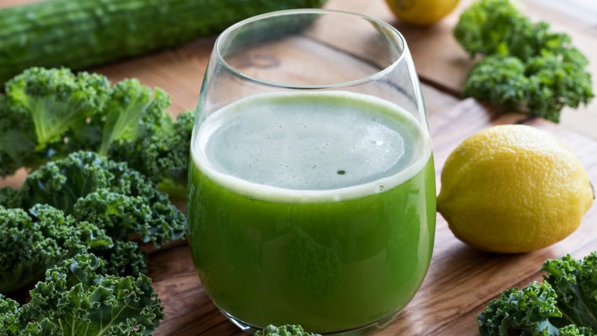 Low calorie green juice ready to drink, looks delicious. Surrounded by some of the ingredients used Kale & Lemon