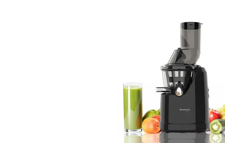 Kuvings C8000J Juicer next to fruits on a white bench