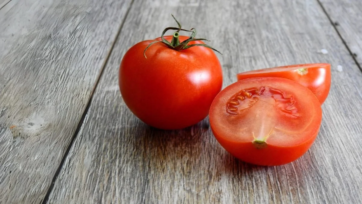 Whole & half tomatoes placed on a wooden board