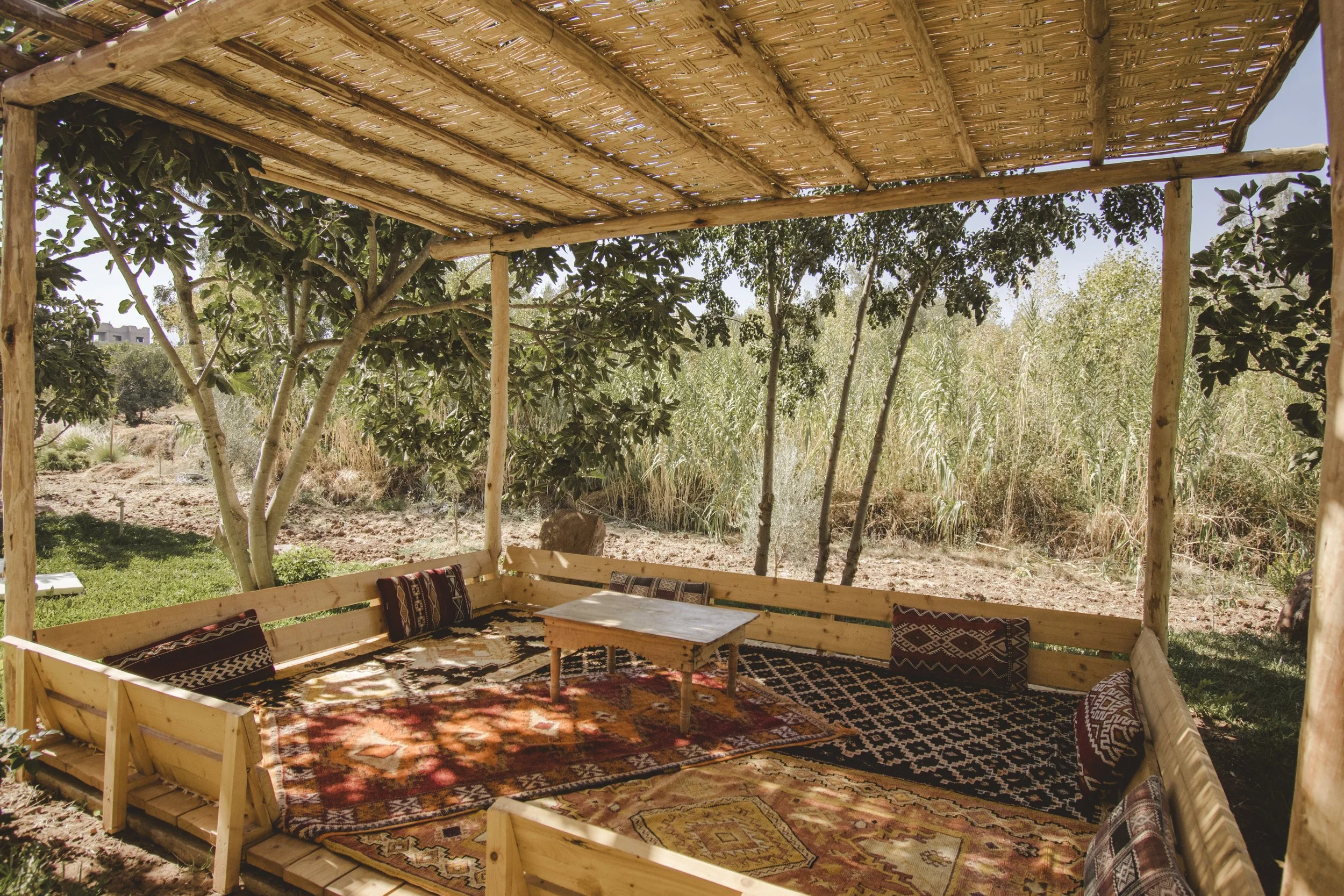 Shaded outdoor lounge with Berber rugs in the gardens at Bab Zouina
