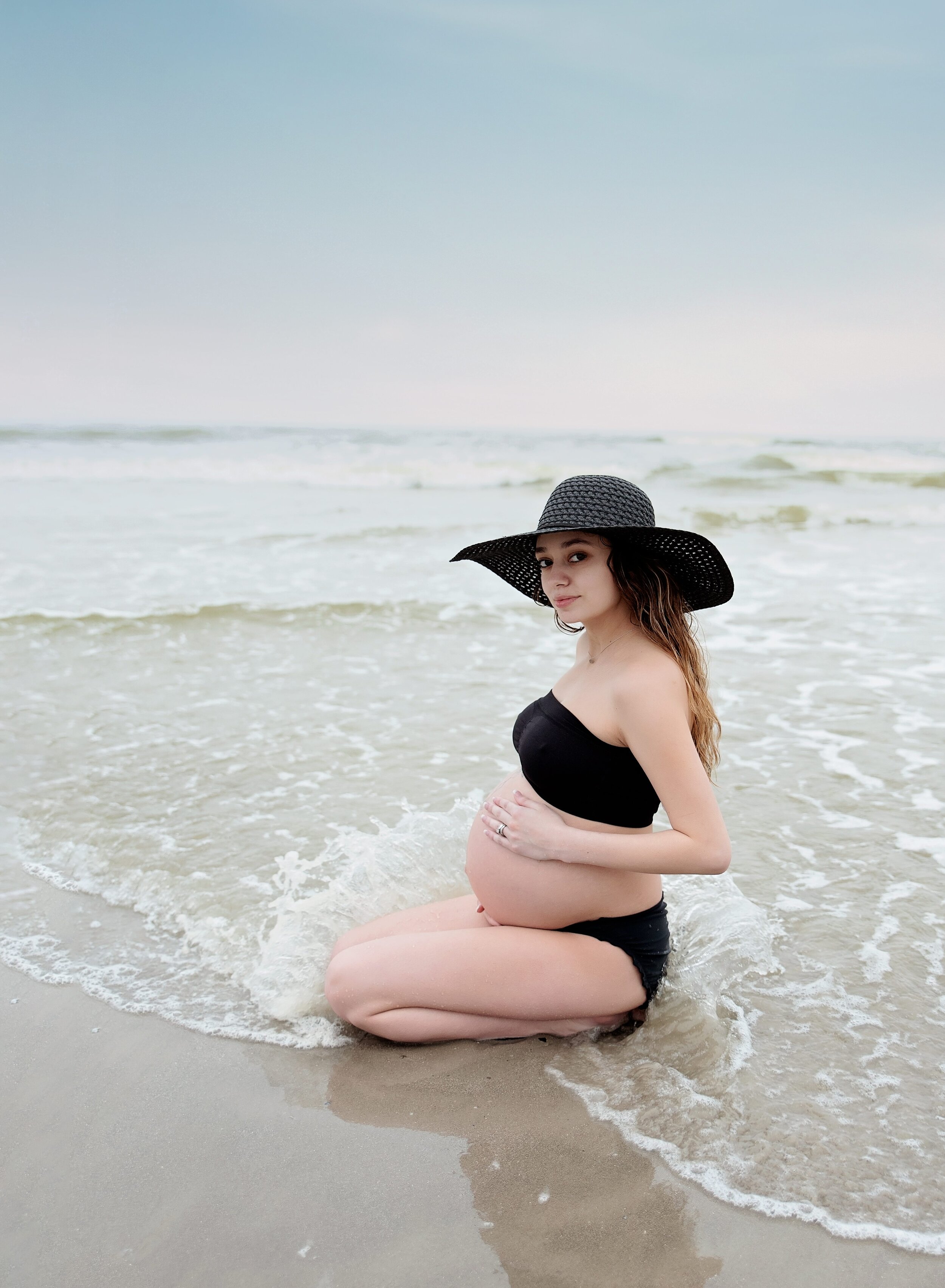 Pregnant mom sitting on the beach in Galveston, TX