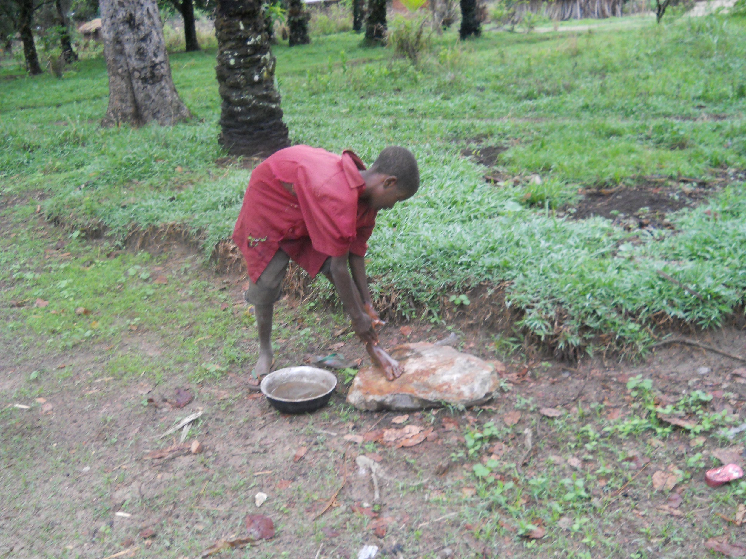 A boy using collected rain water to wash before school.JPG