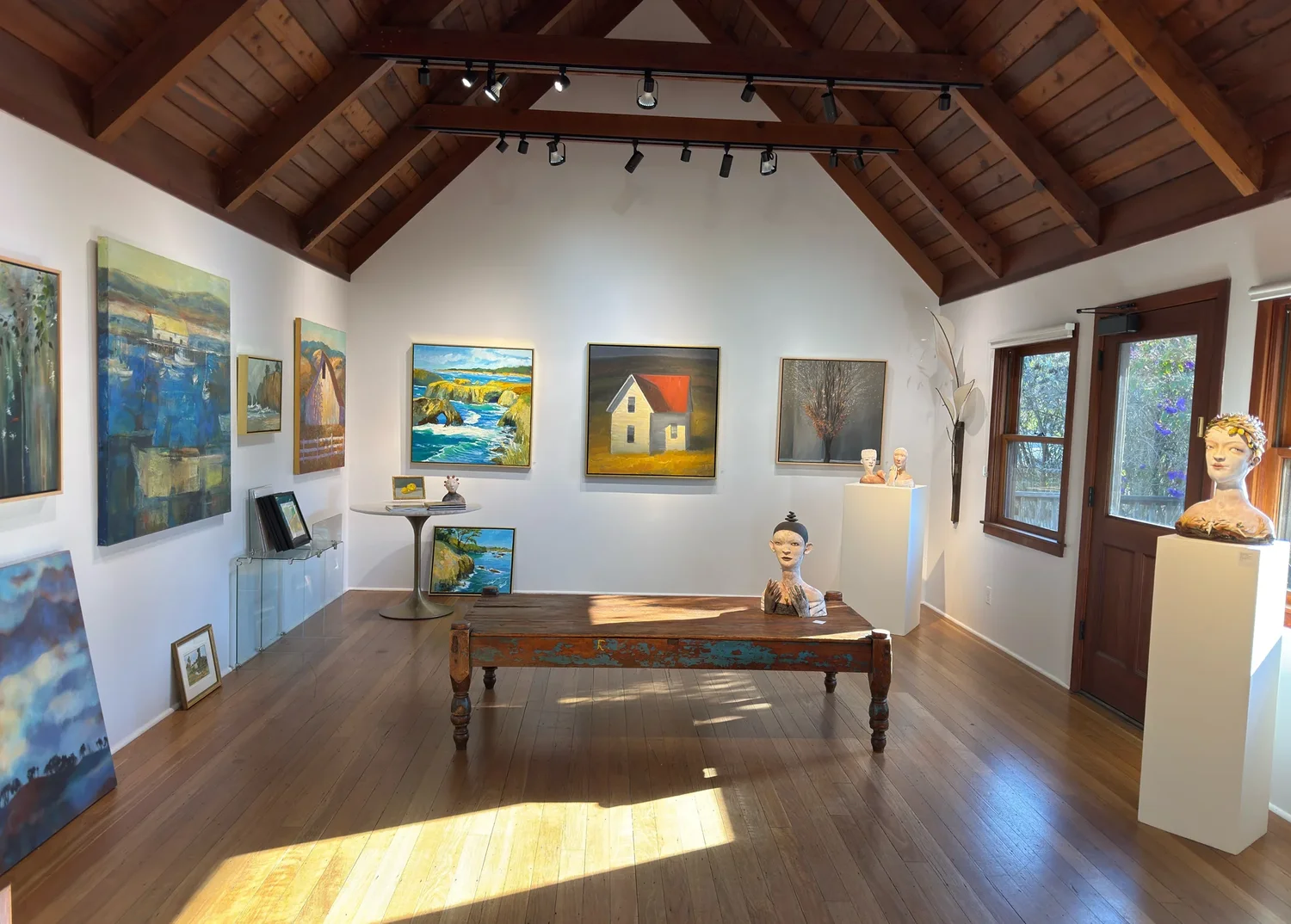 Inside J. Howell Fine Art: paintings and ceramics in a room with a high beamed ceiling