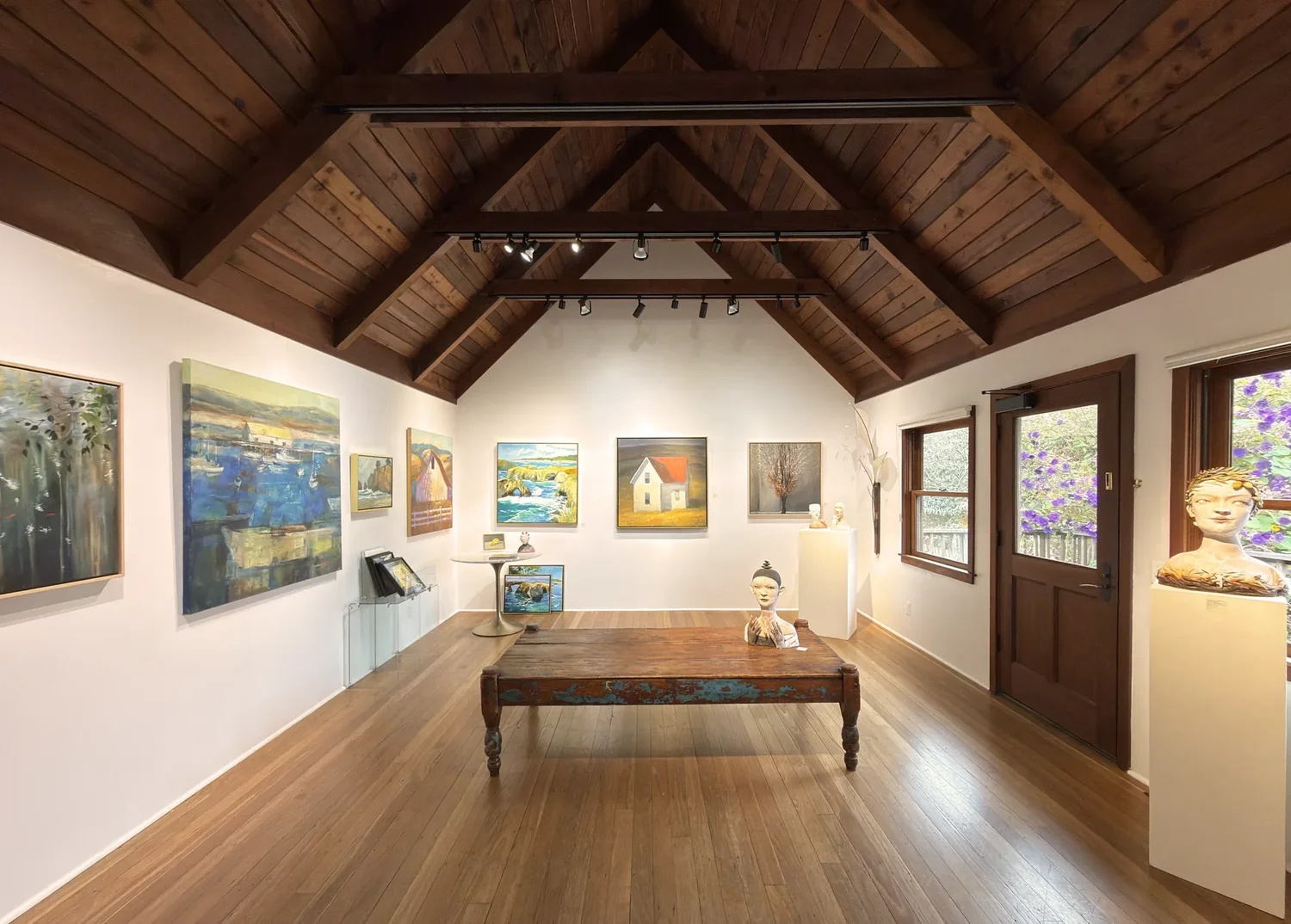 Inside J. Howell Fine Art: paintings and ceramics in a room with a high beamed ceiling