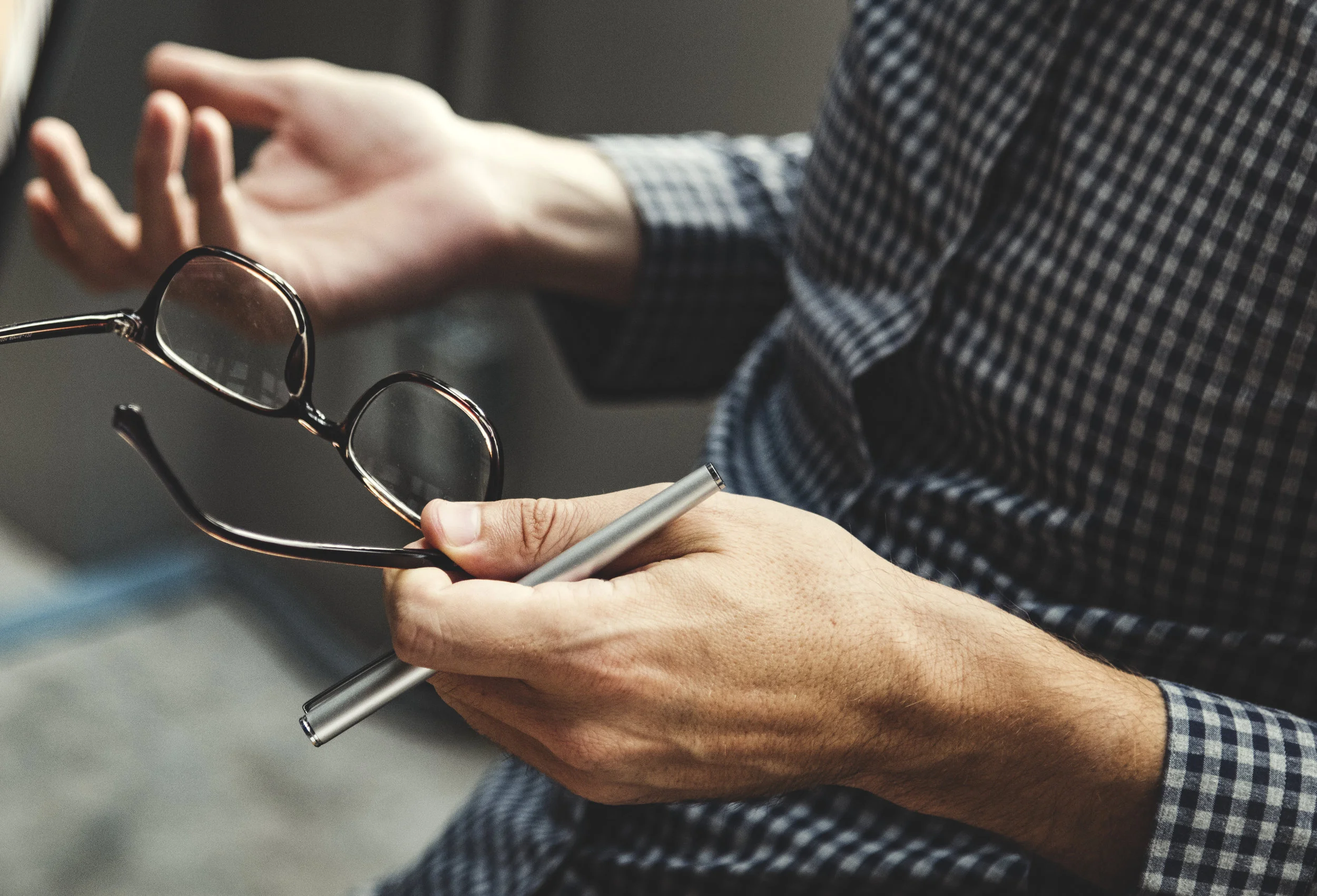 Close-up picture of man holding glasses and pen