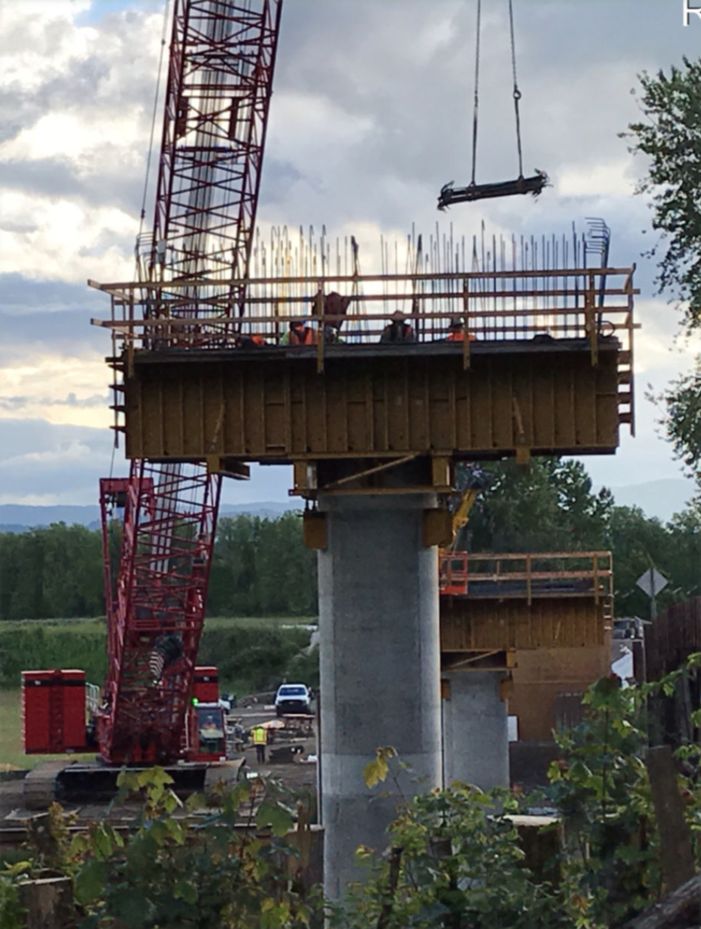 A crane delivers rebar to a pier cap.