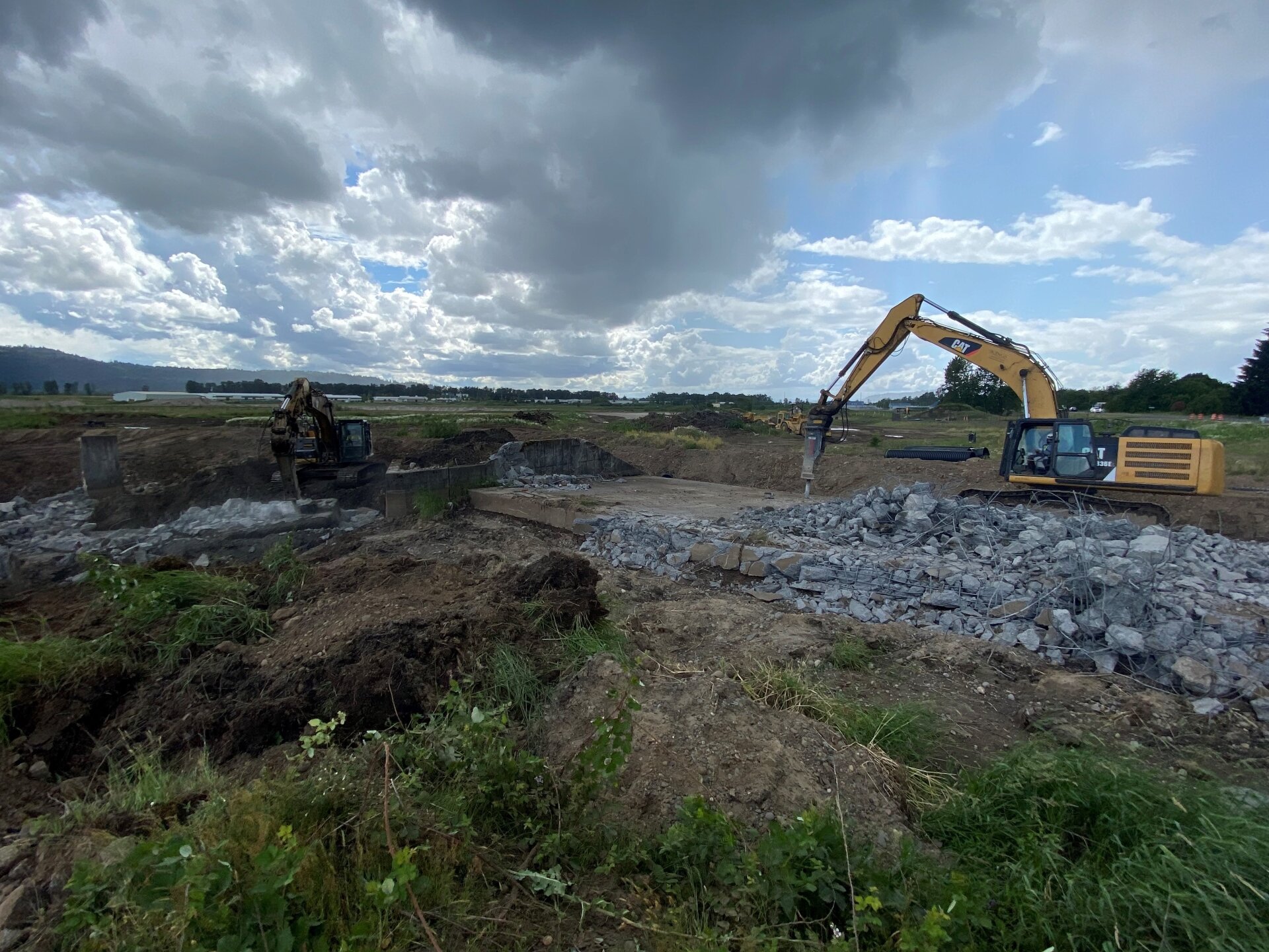 An Excavator with a Hydraulic Hammer attachment breaks apart concrete on the Gibbons Creek diversion structure at Steigerwald Lake NWR.