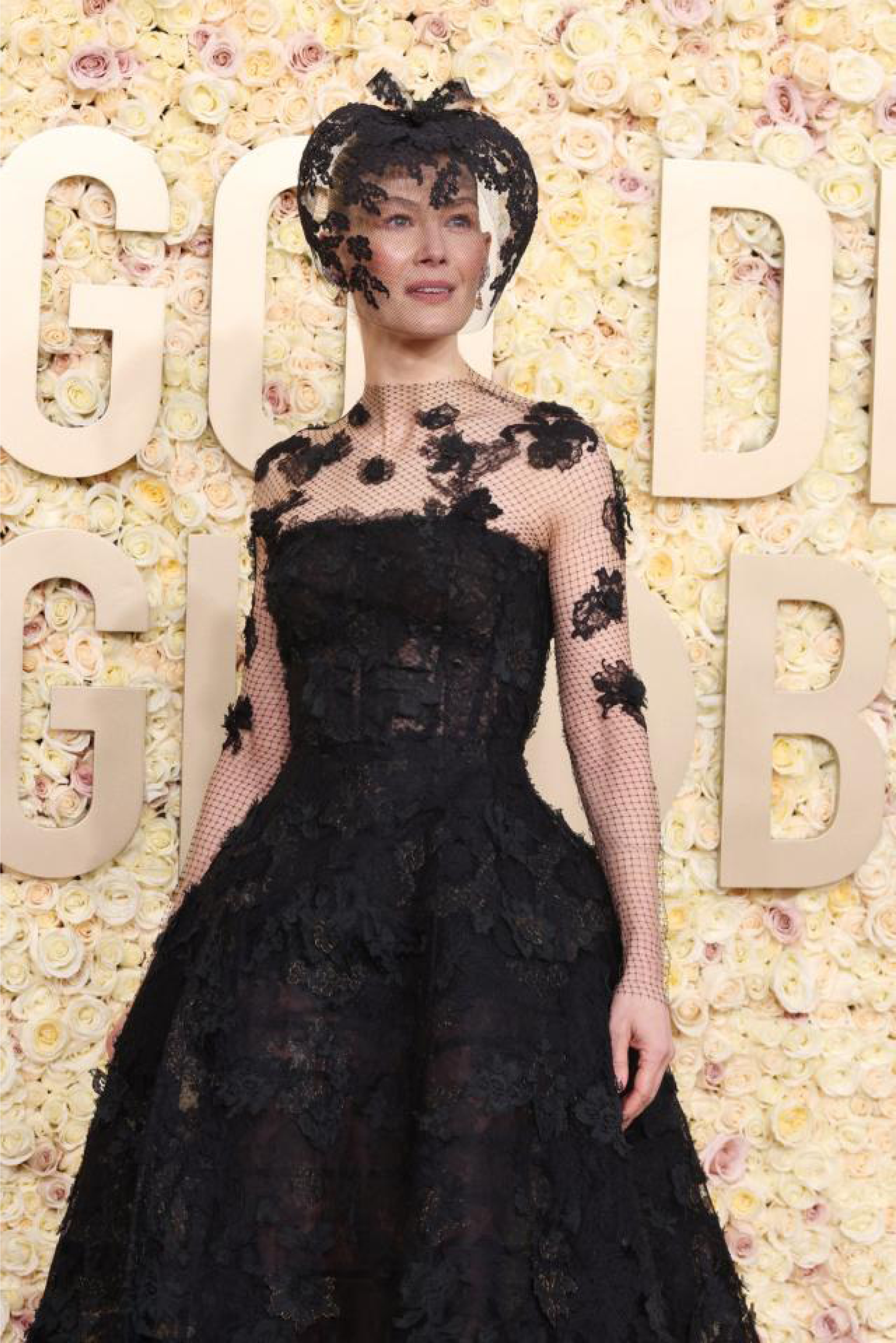 A portrait captures a woman wearing a black lace gown styled with a matching headpiece.