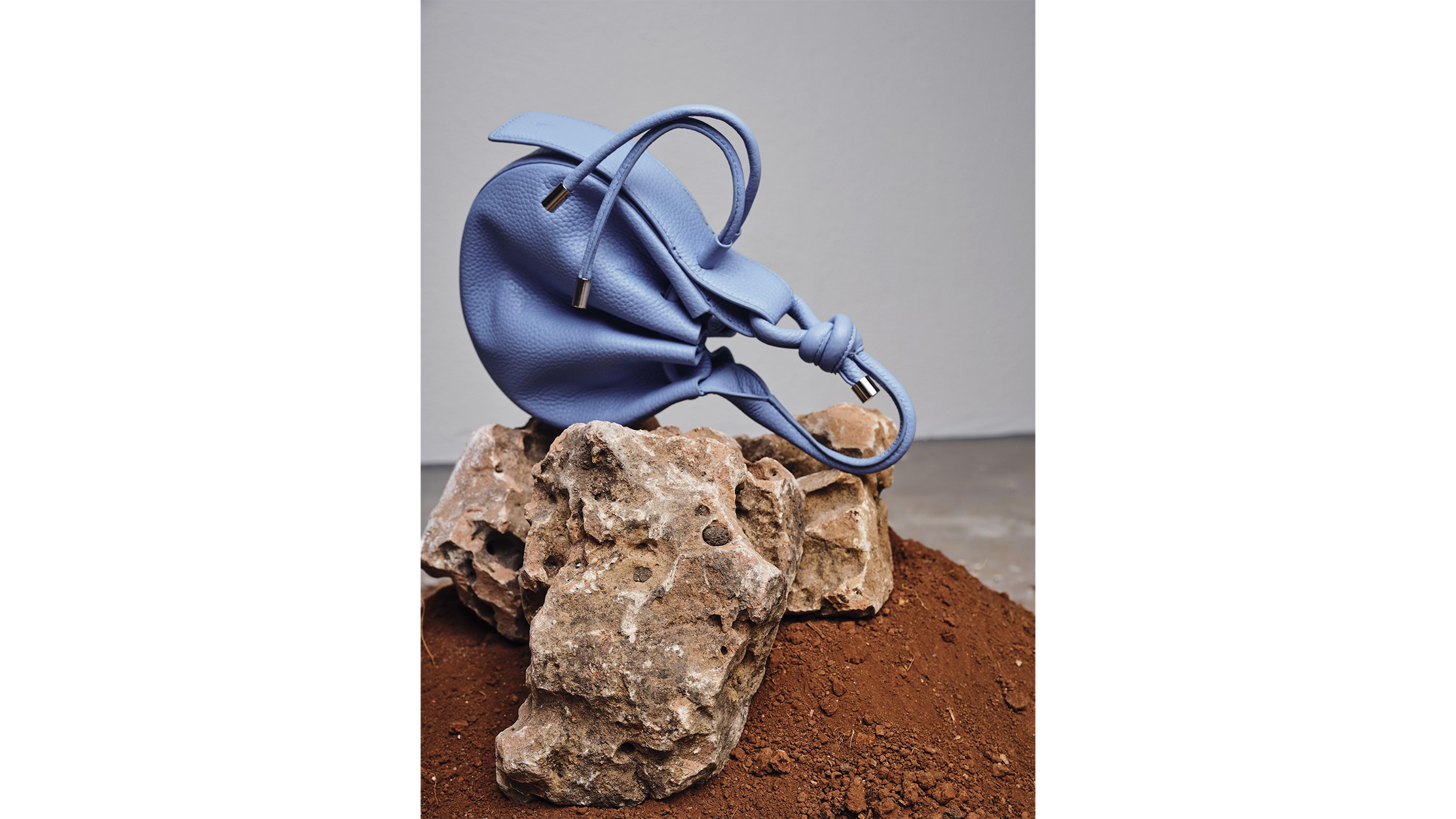 Blue handbag on top of a large rock.