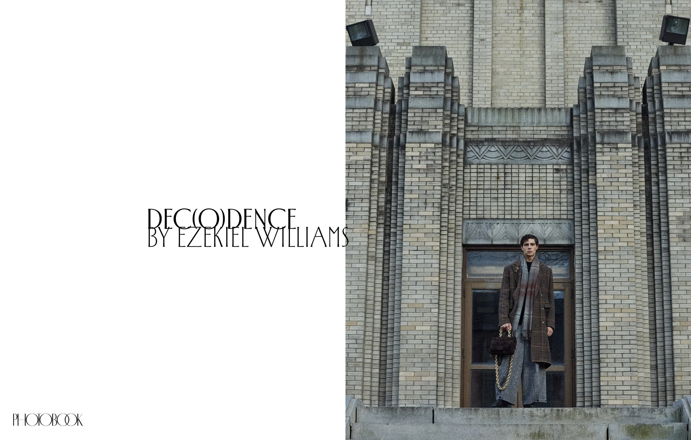 Model is seen standing far away wearing a long coat and a bag in hand.