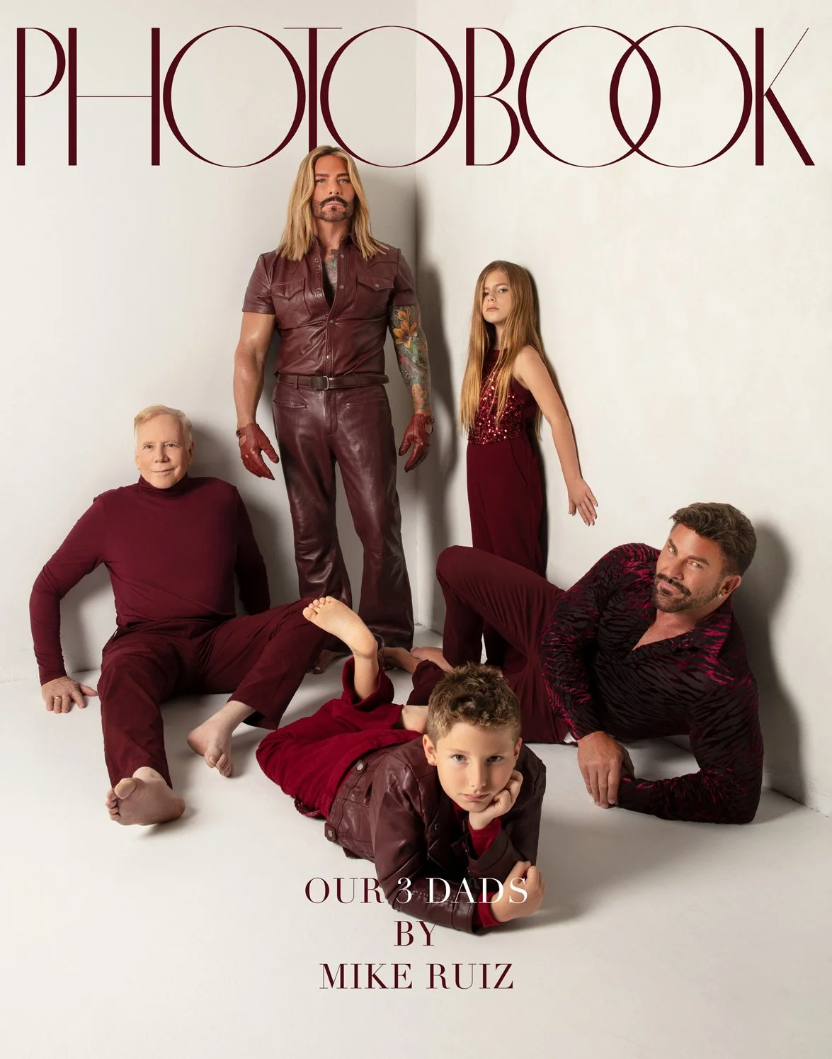 A cover portrait featuring five individuals posed in different stances, all dressed in coordinating shades of dark red.