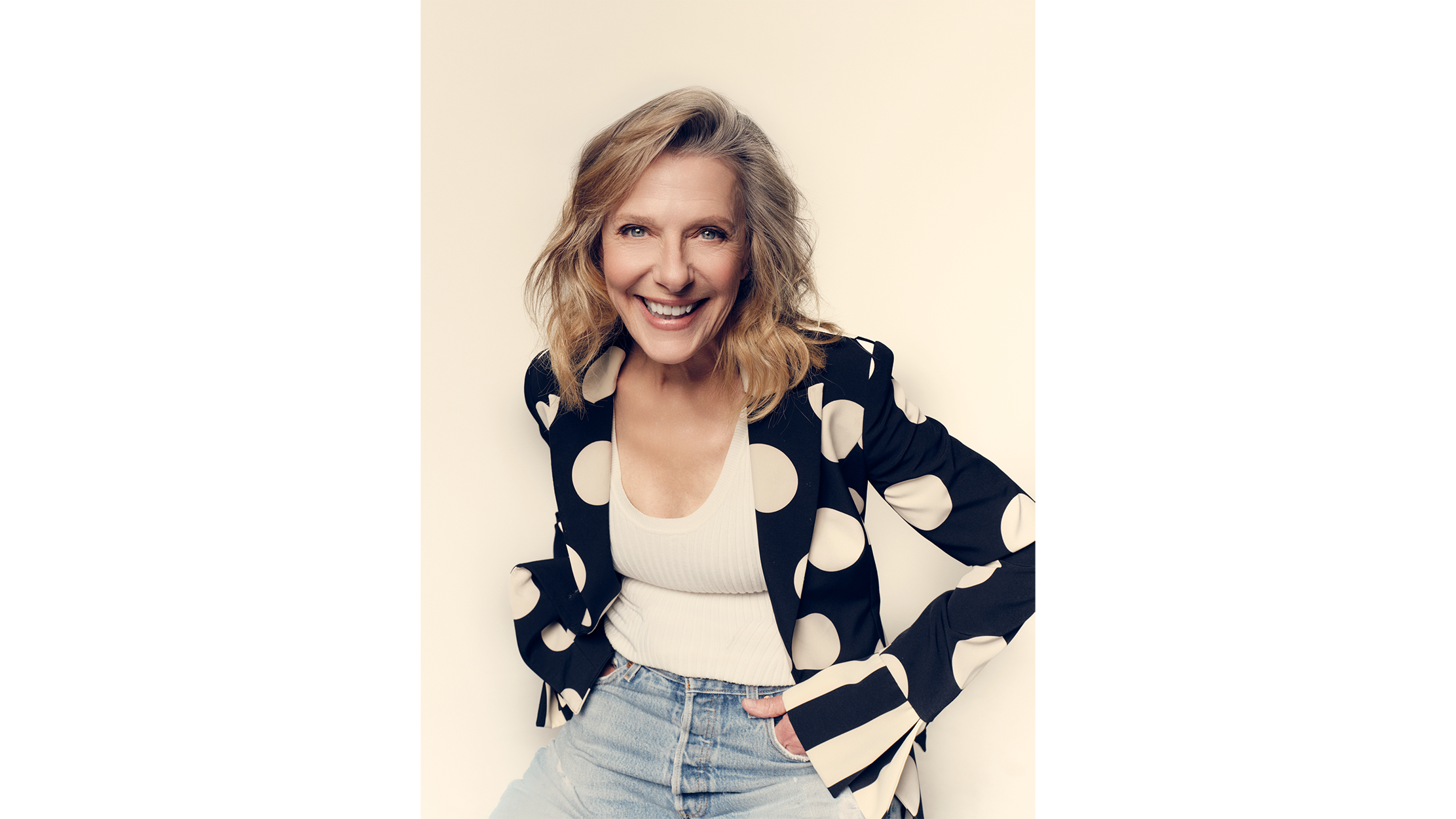 A portrait of Rosalee Mayeux smiling while wearing a black blazer with large white polka dots over a white ribbed top and light-wash jeans.