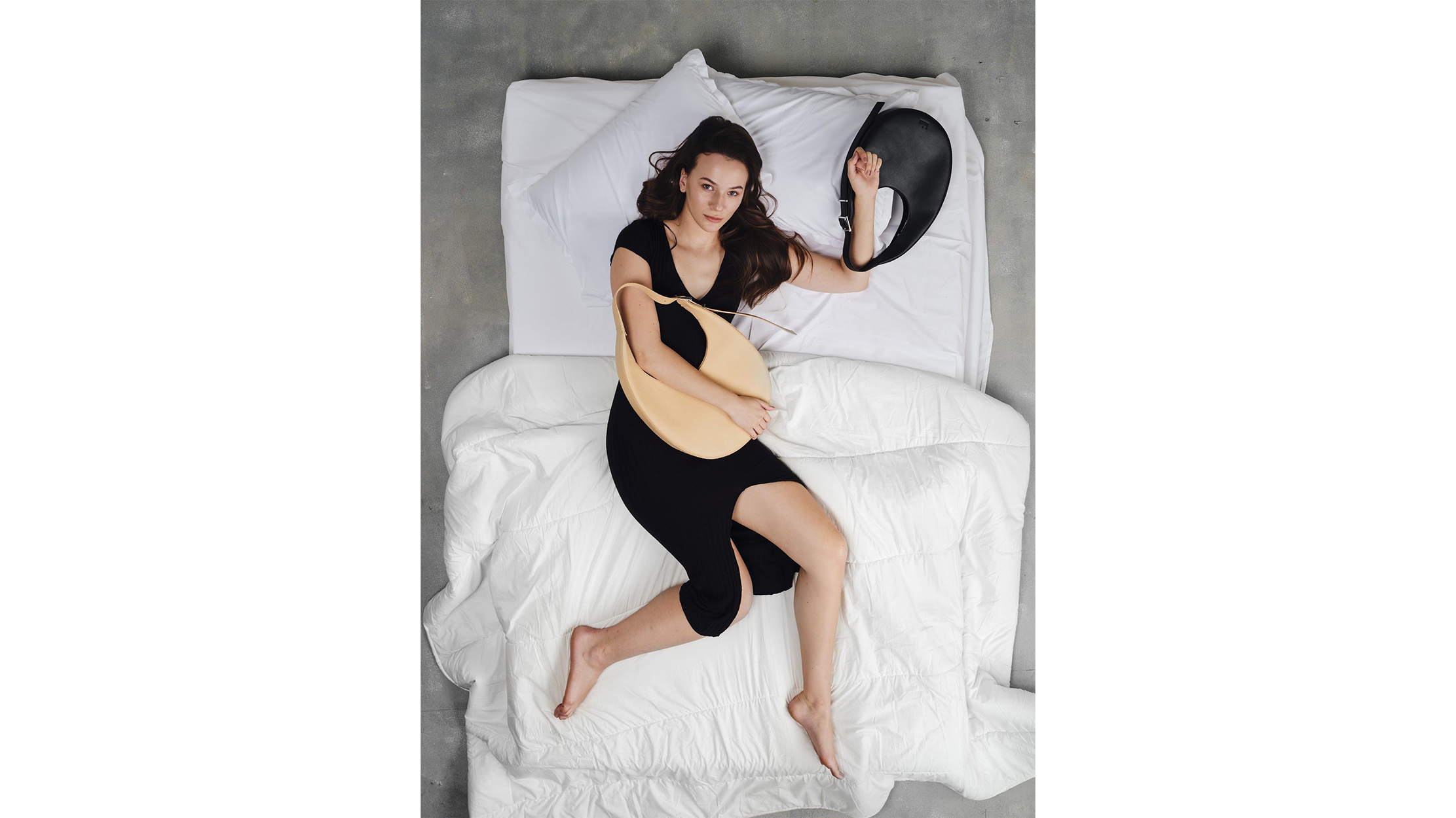 Woman laying on bed holding 2 bags