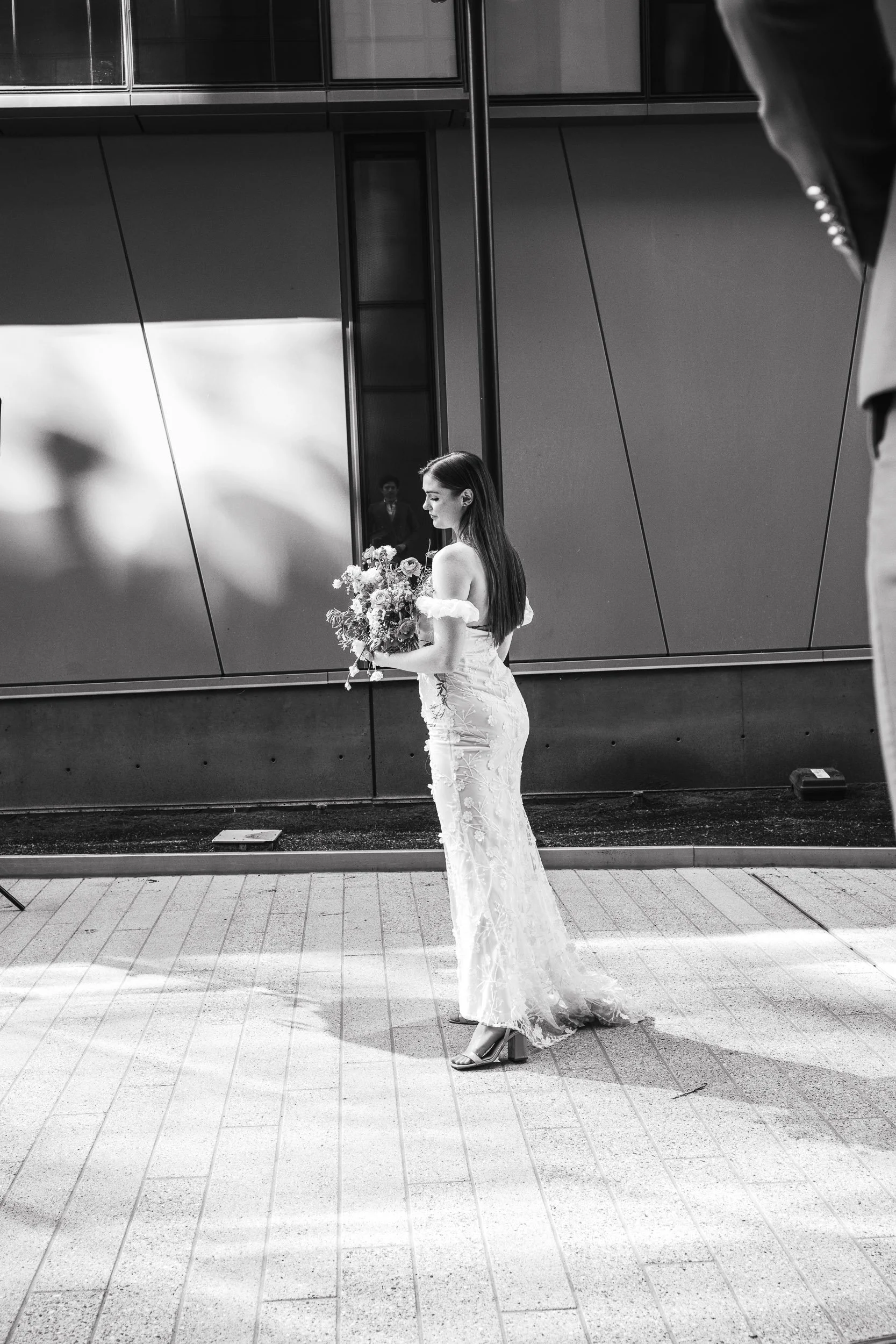 black and white wedding portrait with the groom looking at his bride. He is seen in the reflection.
