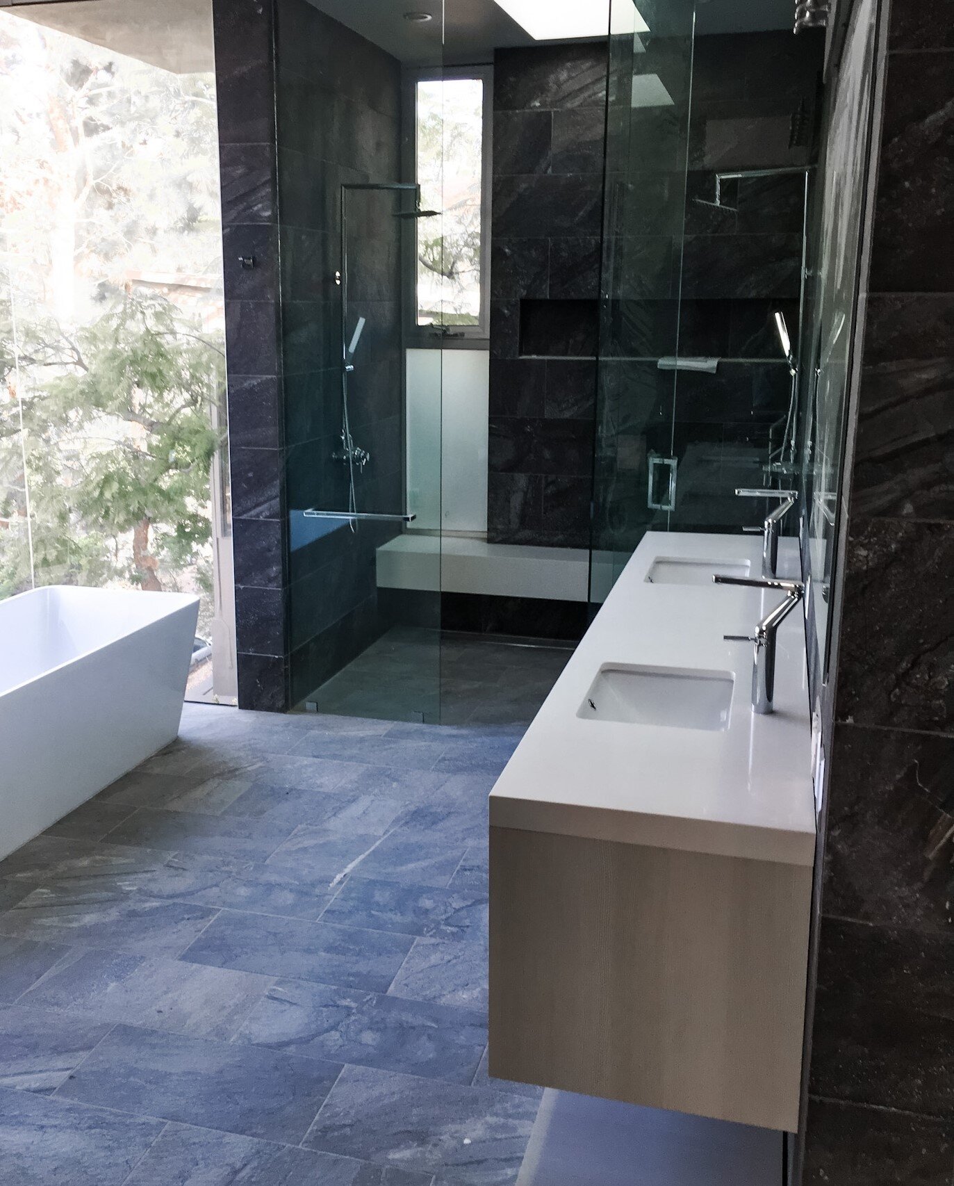 Modern bathroom inspiration from one of our recent projects. How stunning is that raindrop shower with built-in bench, and that view?!