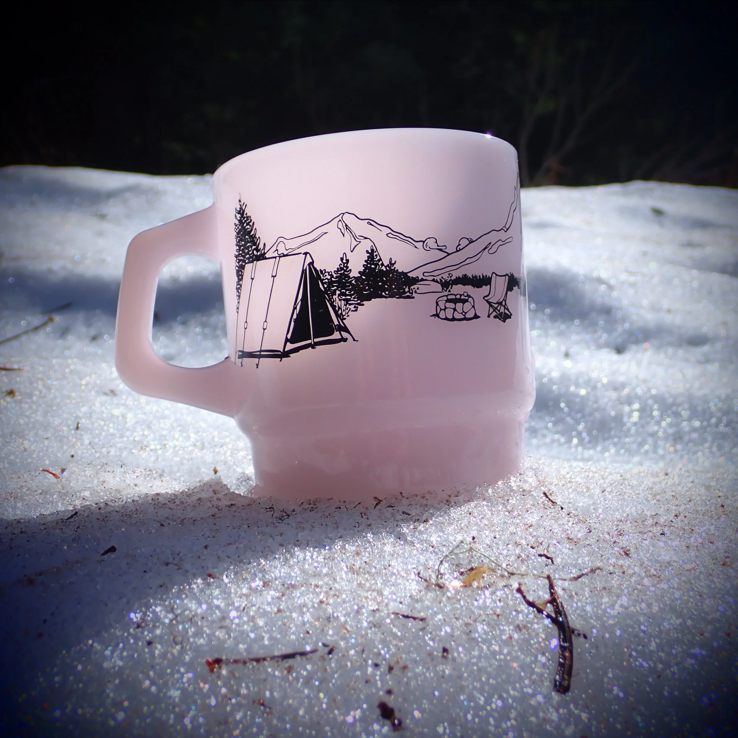 photo of our milk glass mug resting on a snowwy slope with sunlight illuminating the translucent glass