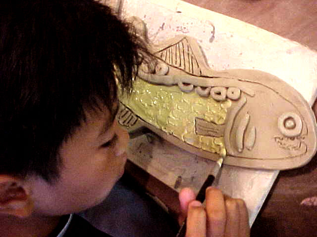  Graham Hill Elementary School, Seattle, WA – Salmon cycle: Teaching component :: 2004.  Boy glazing a salmon. The younger children worked on a different project each time they came, but older ones would come back and glaze something they made in a p