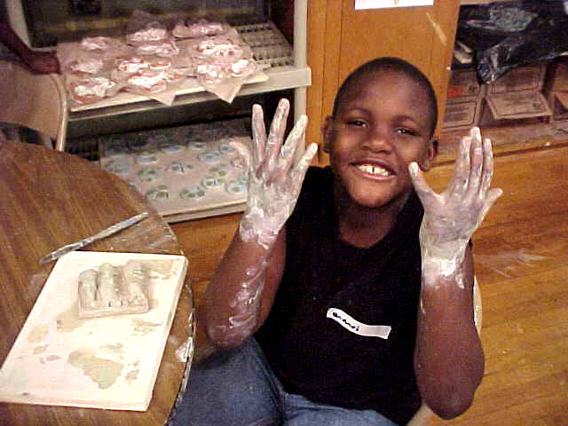  Graham Hill Elementary School, Seattle, WA – Salmon cycle: Teaching component :: 2004.  Making tiles. This student is working on making a letter tile for the poem wall. Deirdre and Julia prepared the slabs of clay for the tiles, and then the childre