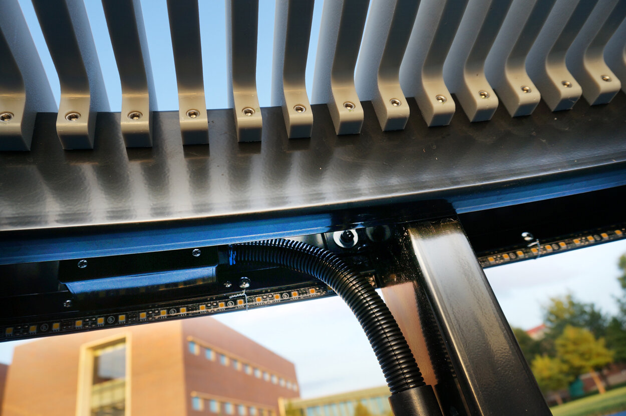                   The Exchange, KU Edwards, Overland Park, KS :: 2017.    Detail of the underside of the bench from the inside curve, showing slat attachments, power stub-up connections, and the lighting strips.     