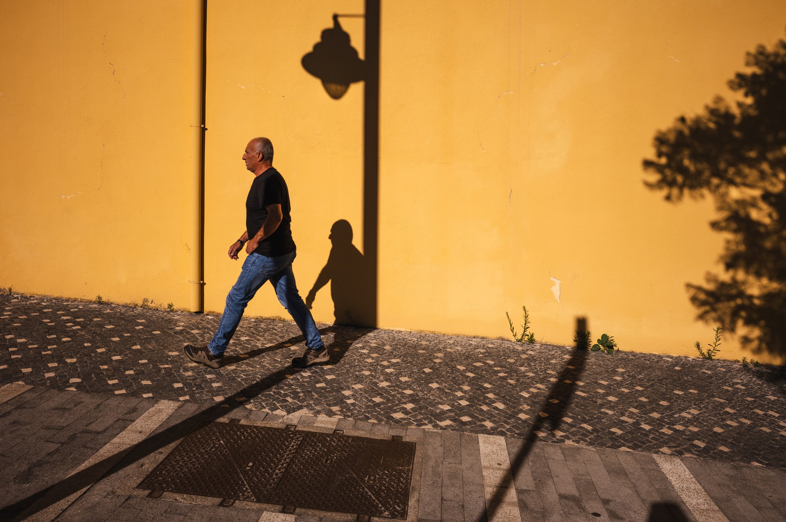 Man walking beside a yellow wall.jpg