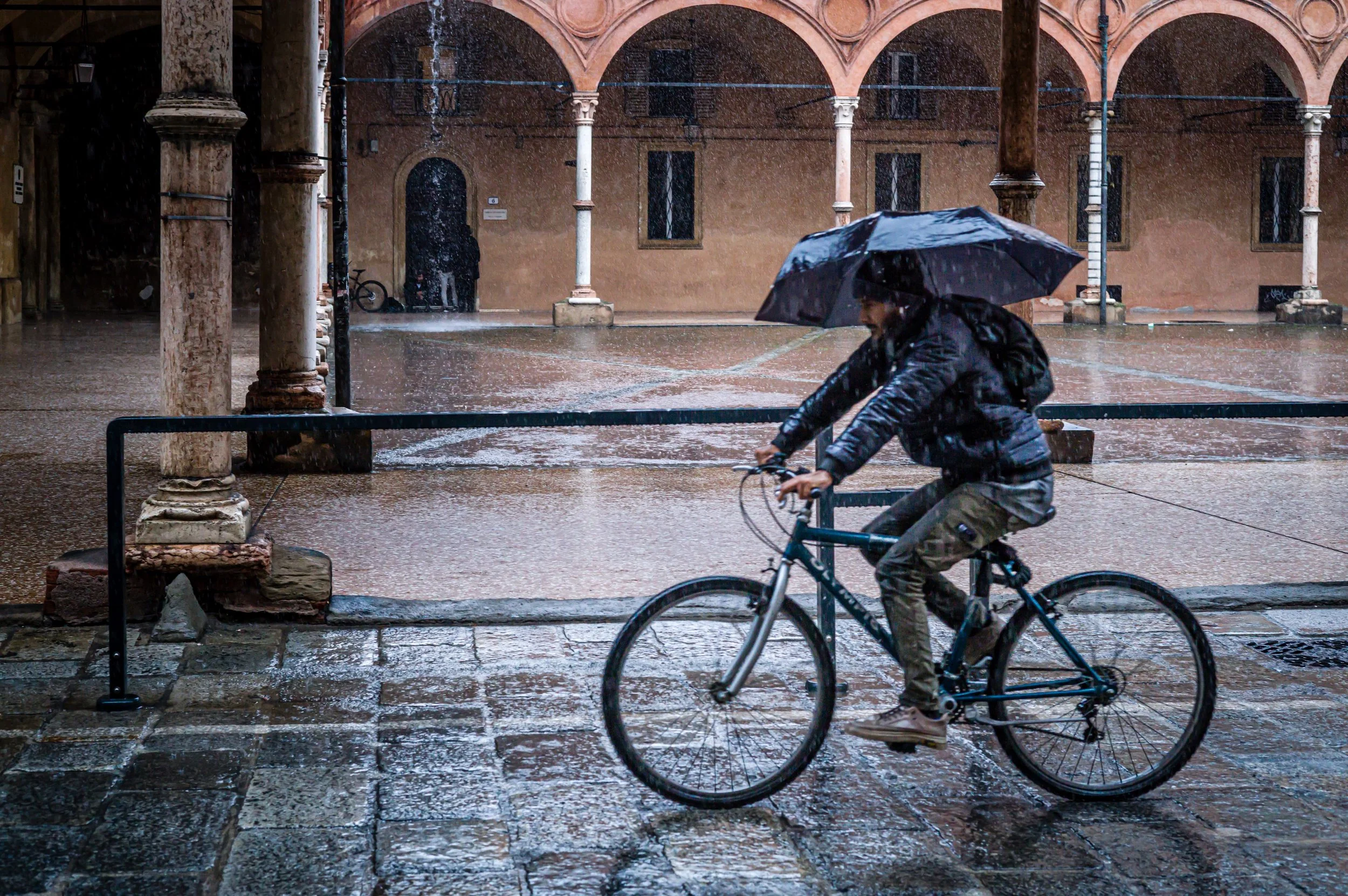 Man cycling in the rain with an umbrella.jpg