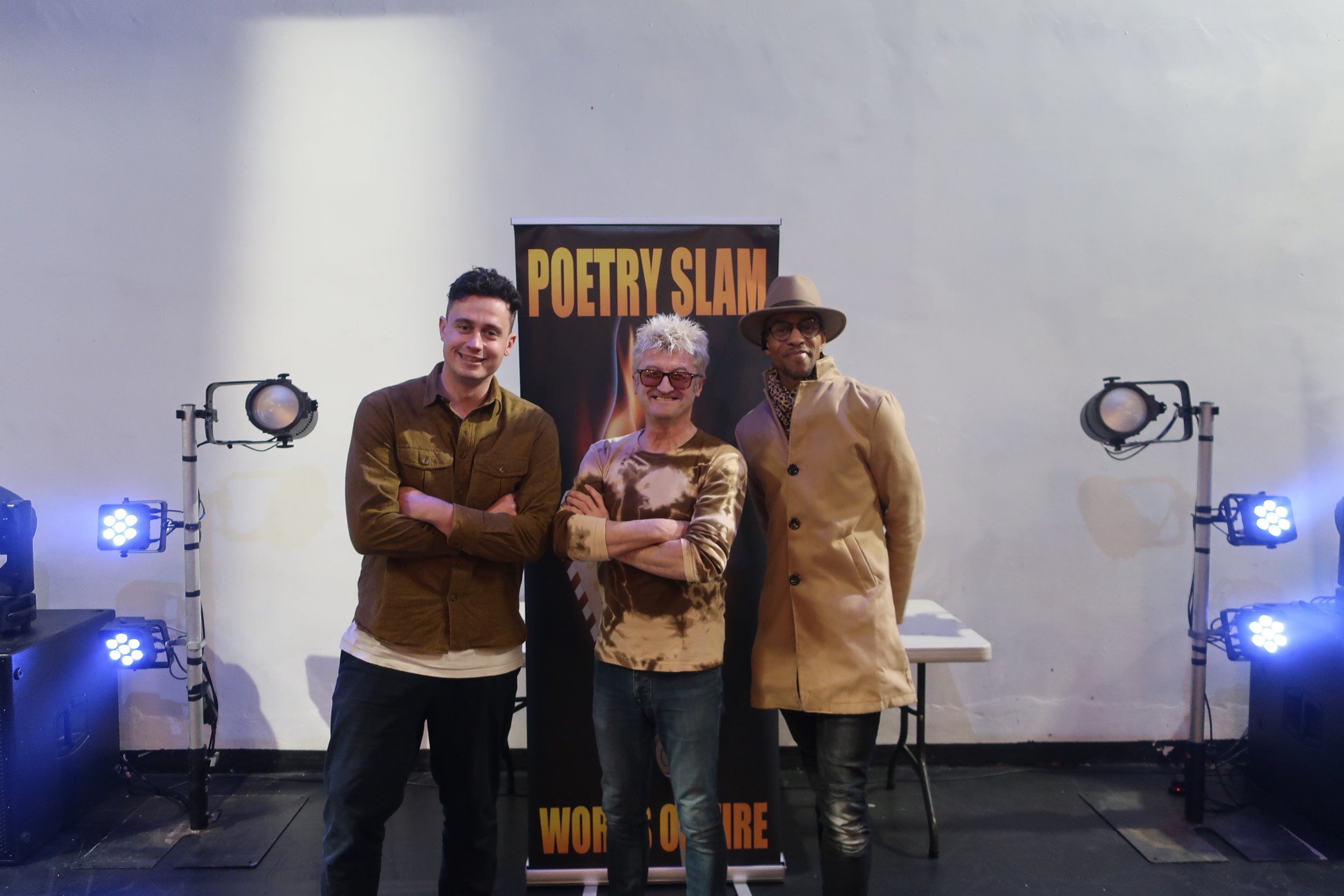 3 poets posing in front of banner.JPG