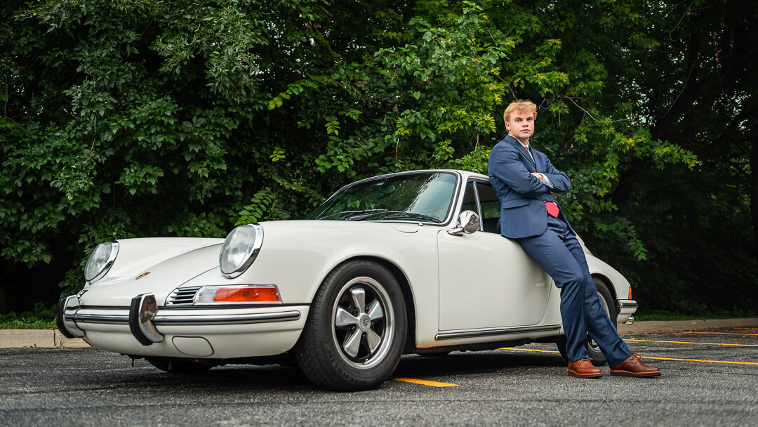 Omaha senior pictures high school guy leans against vintage Porsche