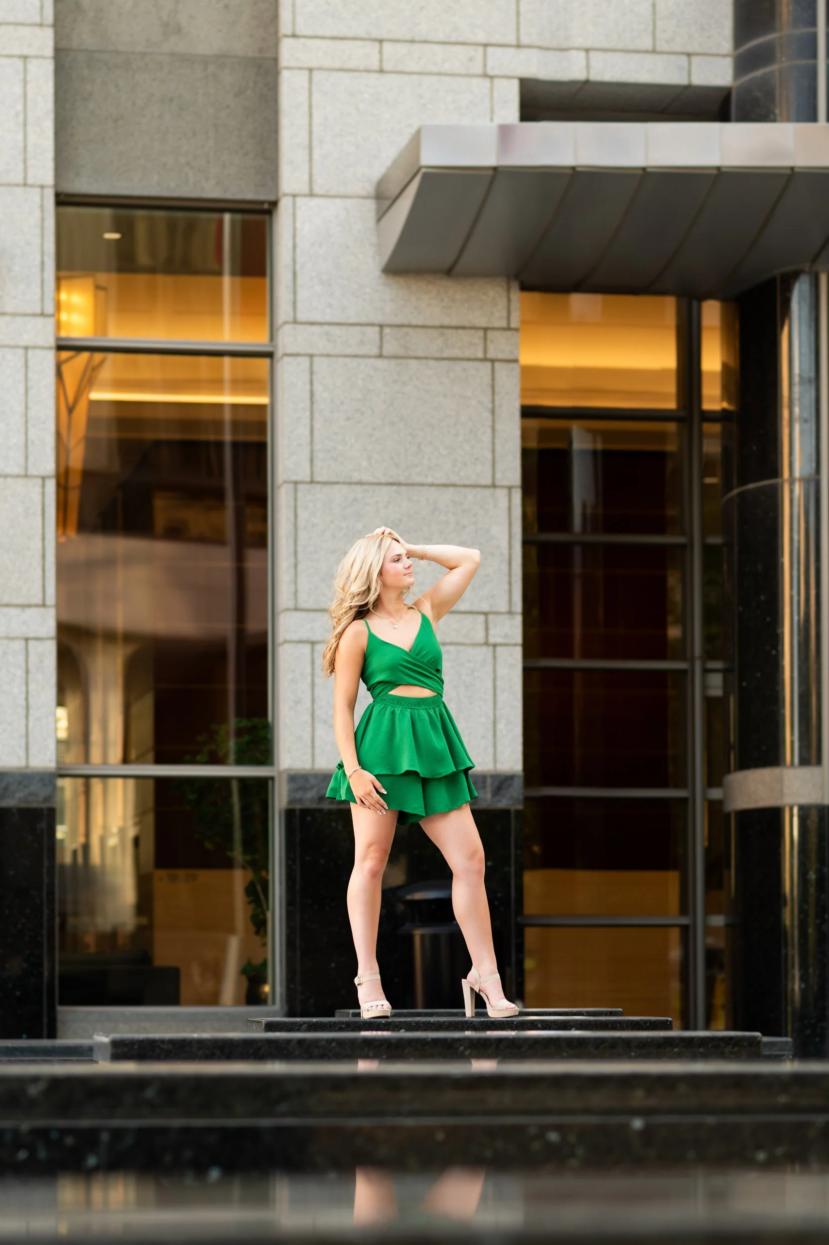 senior-girl-green-romper-standing-black-marble.jpg