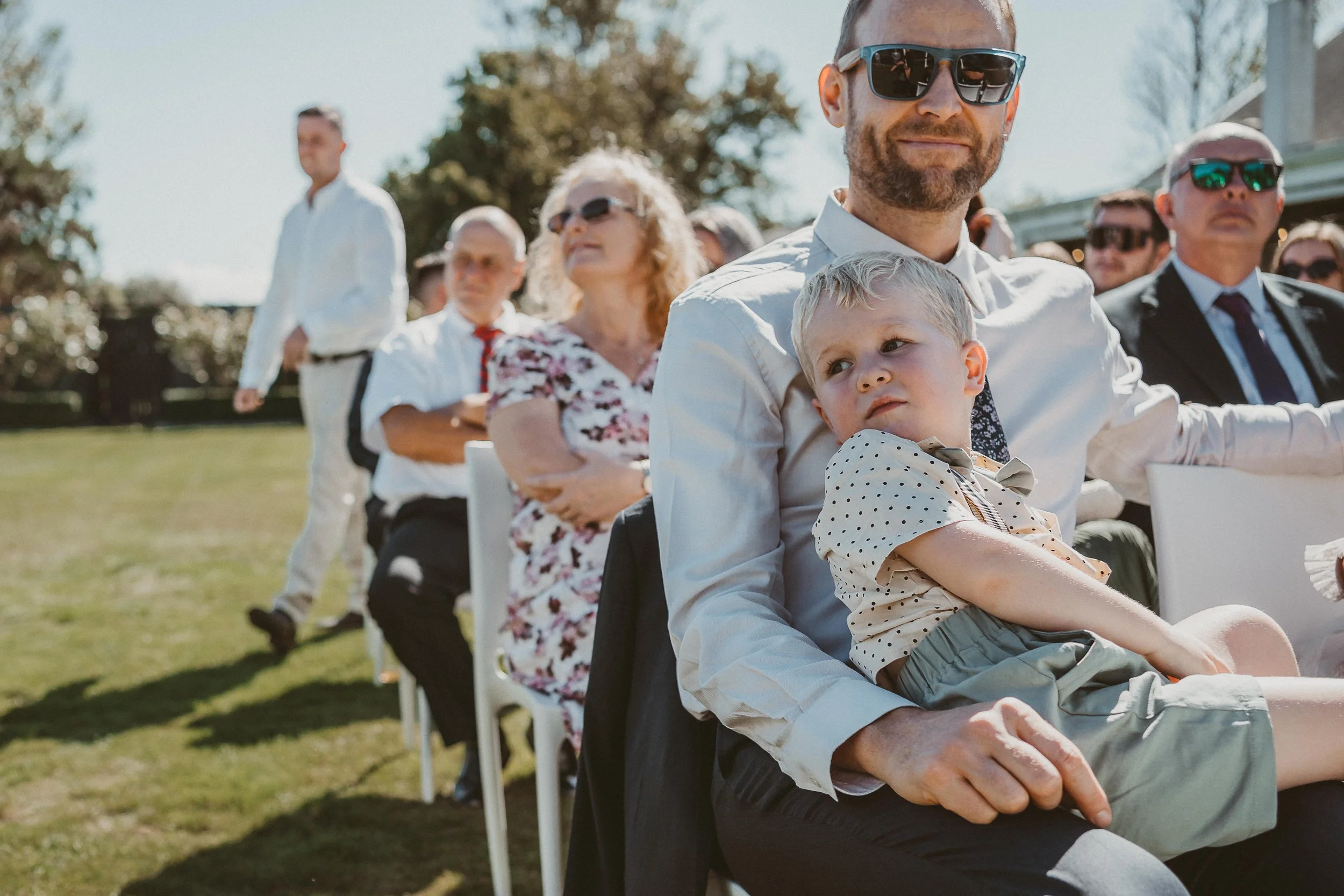 Child sitting on dad's lap during wedding ceremony