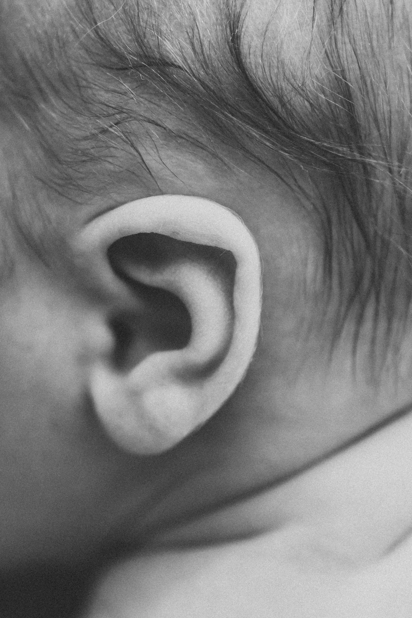 Close-up black and white shot of a newborn baby's ear