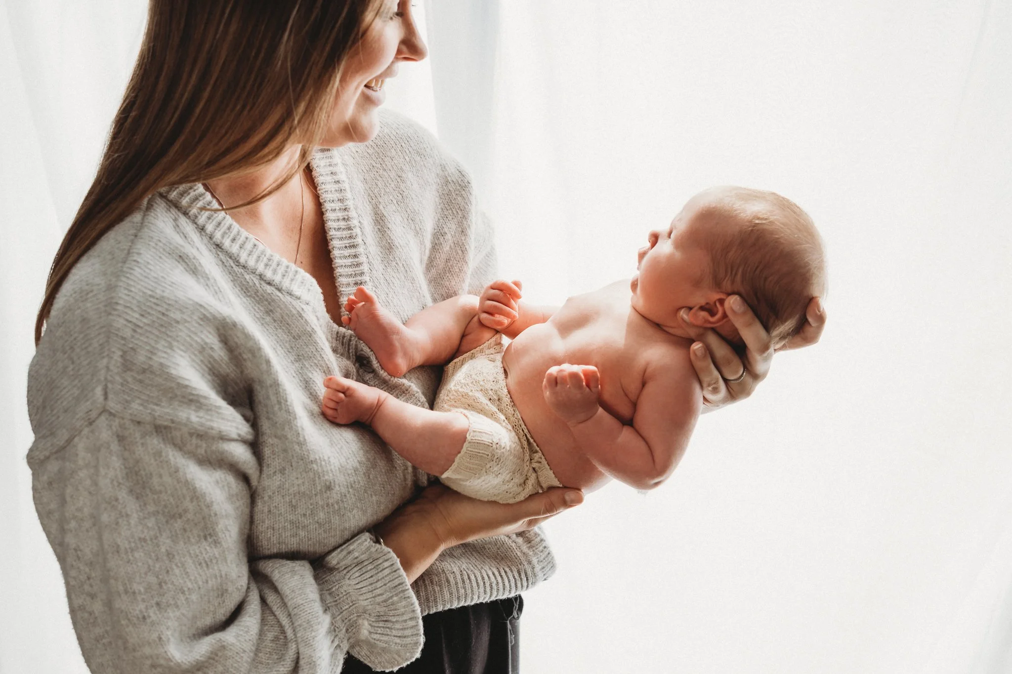 Timeless and beautiful image of mother looking down at her baby in her arms.