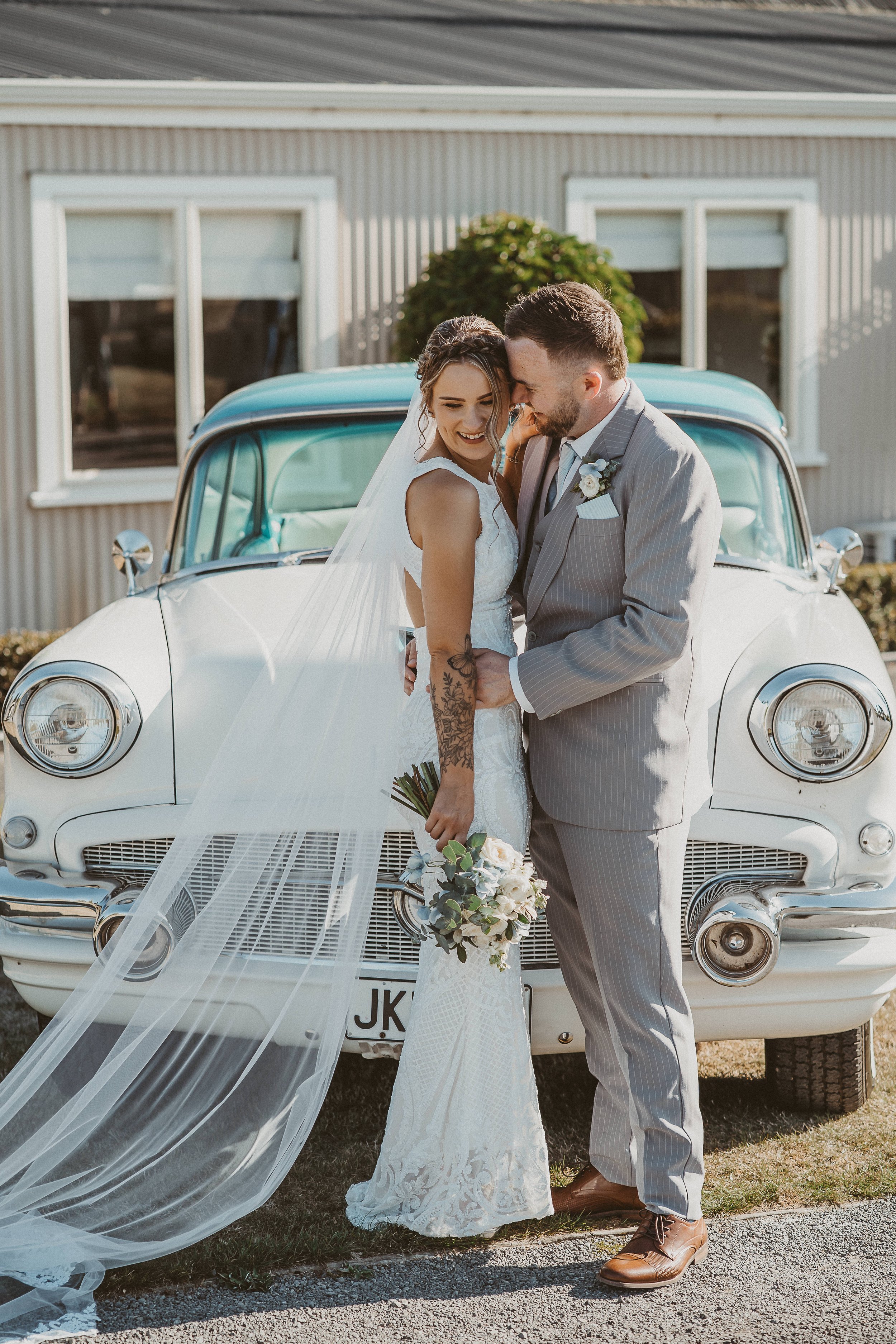 Bridal couple standing in front of a classic car