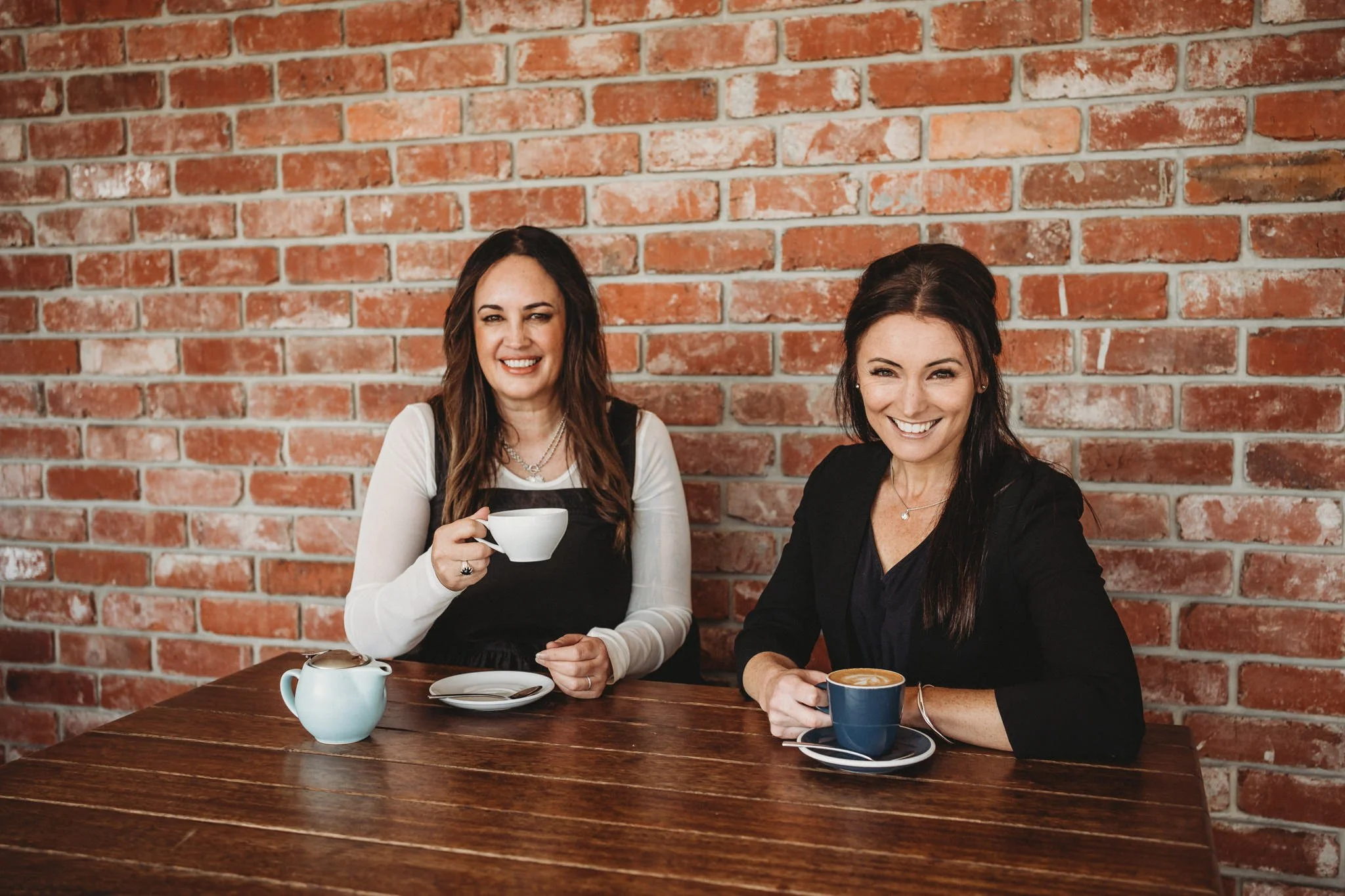 Casual headshot of two women in business having coffee together.