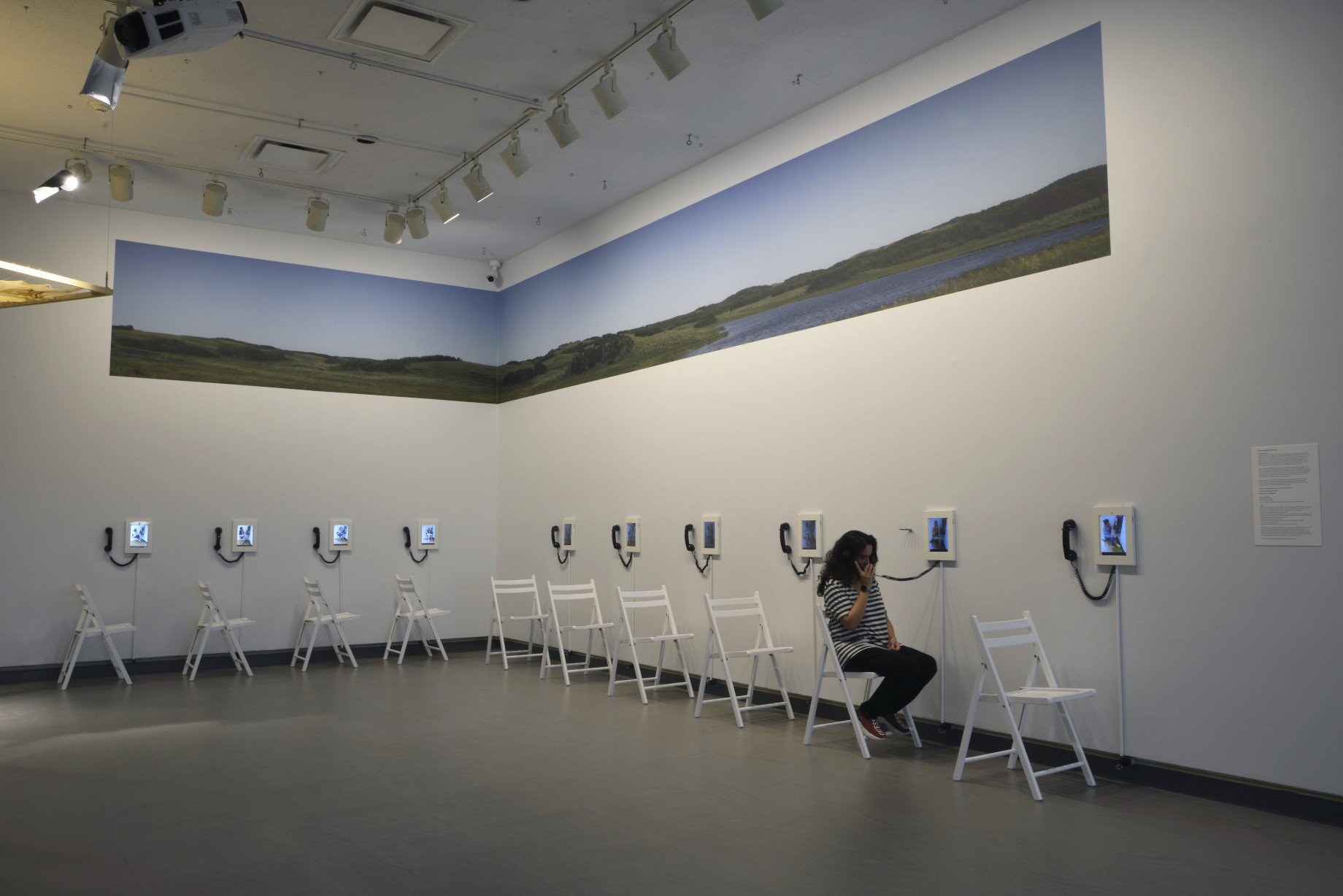   Here I Am (Bless My Mouth) , 2013, multimedia installation, 10 Acer Tablets in holders with handheld telephone receivers and panorama. 