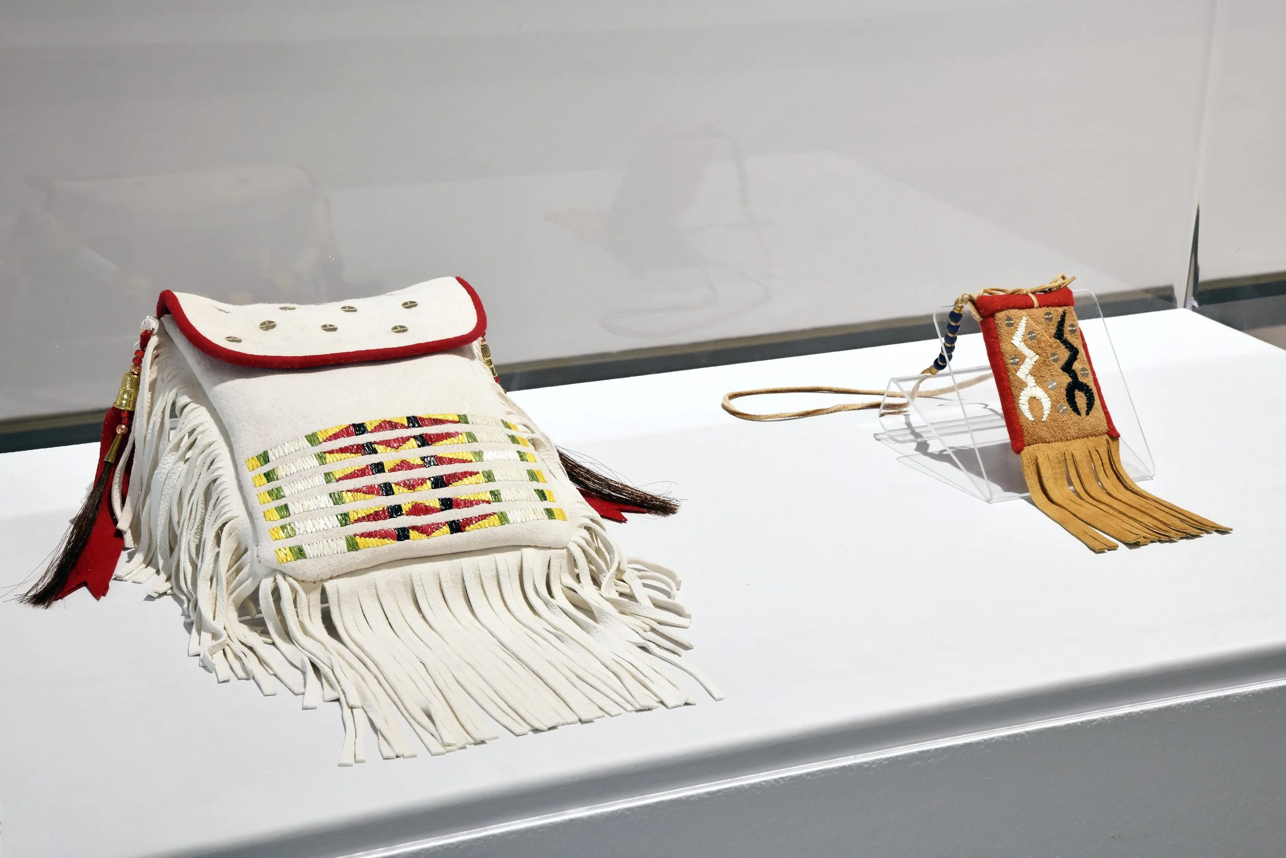  (Left to right)  Serene Weasel Traveller,  Kaayaiss (quillwork deer hide bag) , 2026, deer hide, porcupine quills, seed beads, wool, sequins.  Serene Weasel Traveller,  Thunderbird Medicine Pouch , 2024, smoked elk hide, deer hide, porcupine quills,