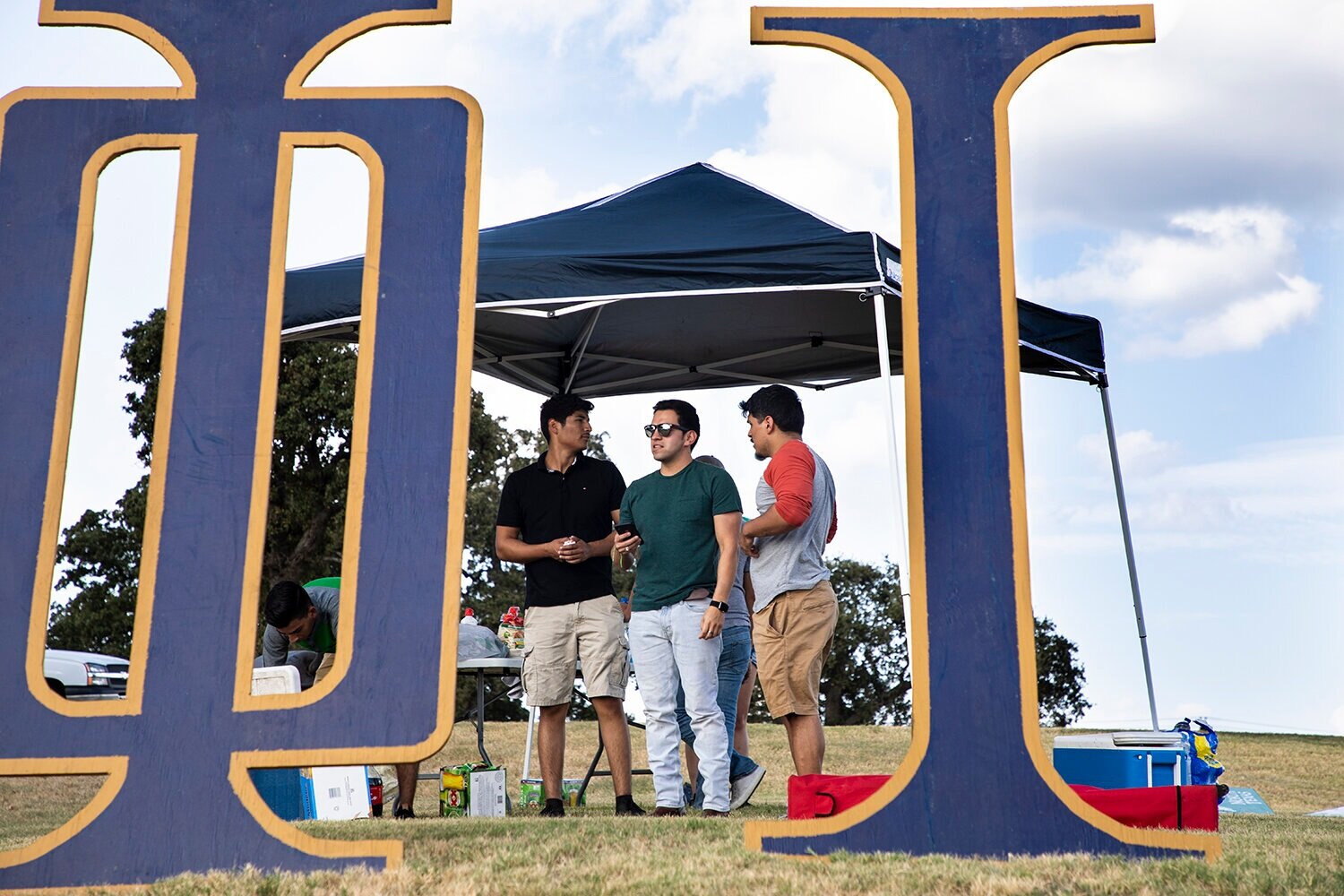 Members of the Phi Iota Alpha fraternity stand together at their tailgate tent before the game against Texas-San Antonio on Sept. 21, 2019. Image by Jordan Collard