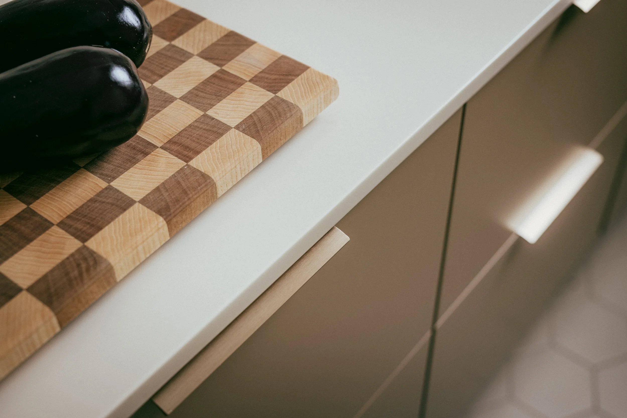 Custom kitchen detail with warm neutral cabinetry, light worktop and natural wood accents designed by Studio Siru.