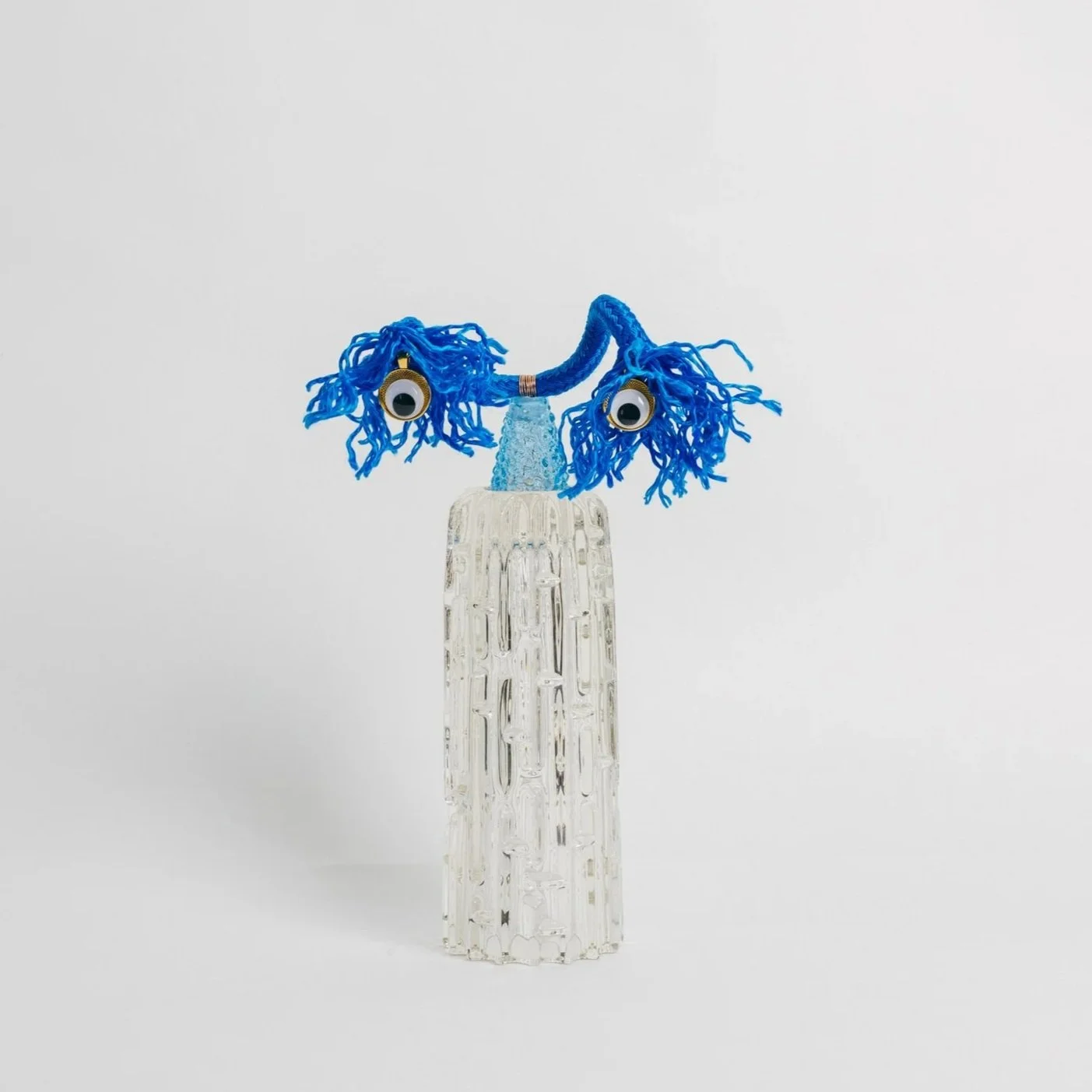 Enlightened Iceman is part of the Second Chance Collectible Art, it was exhibited at the Florence Biennale where also Tim Burton participated Glass sculpture resembling a human face with blue yarn hair, googly eyes, and a tall, textured glass neck.